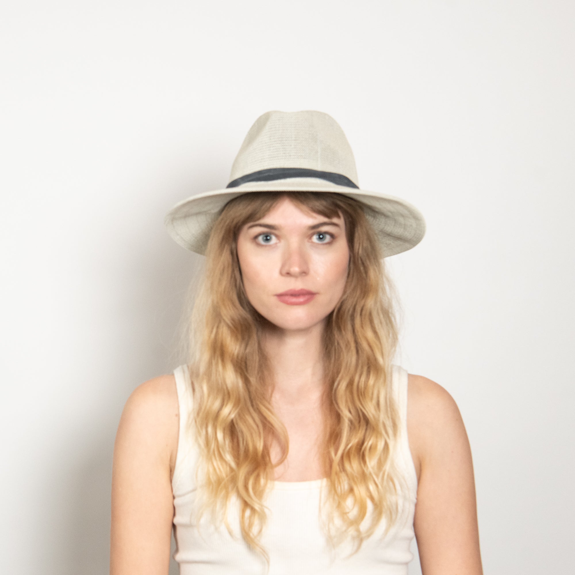 Woman wearing a beige hat against a plain background