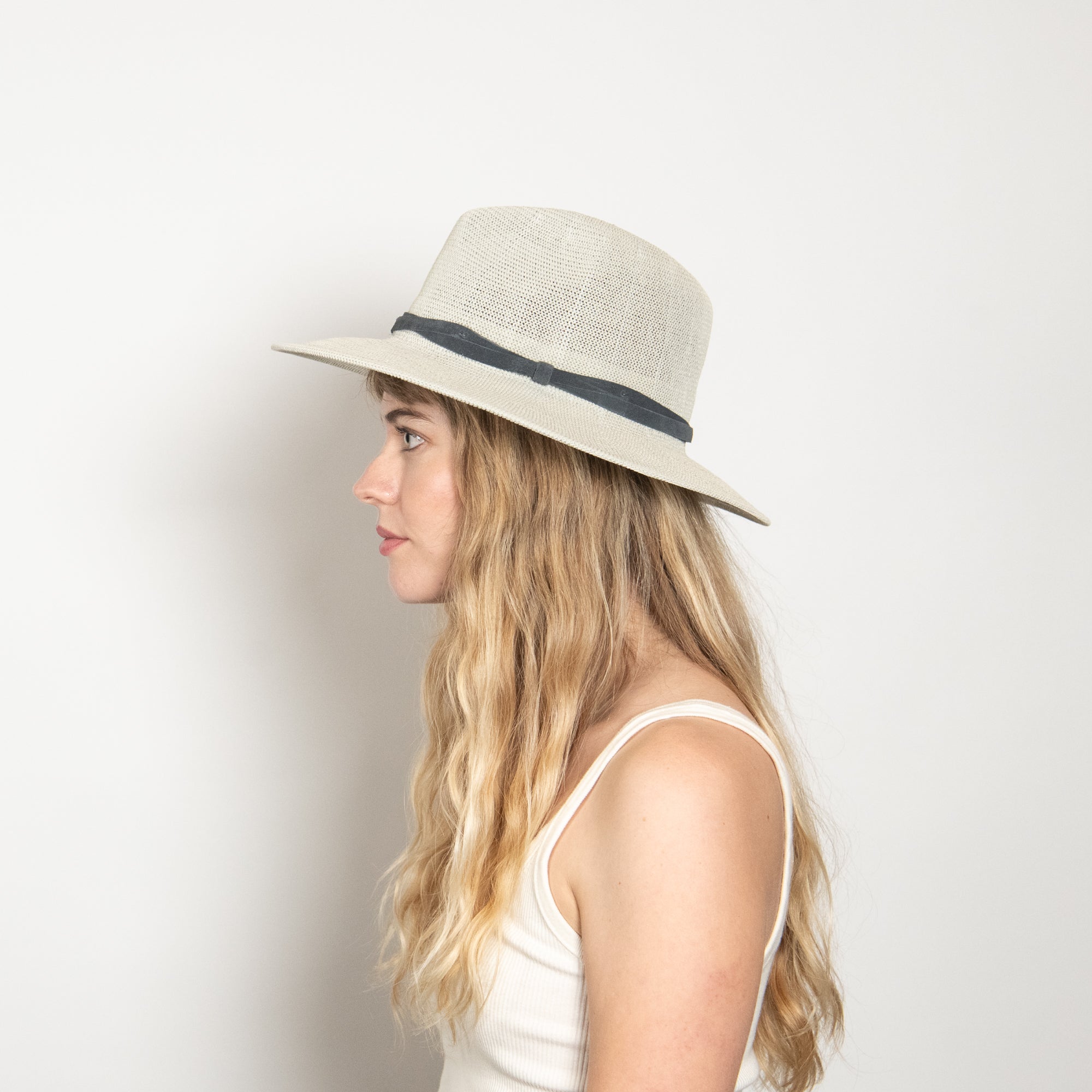 Woman wearing a beige hat with a black band on a white background