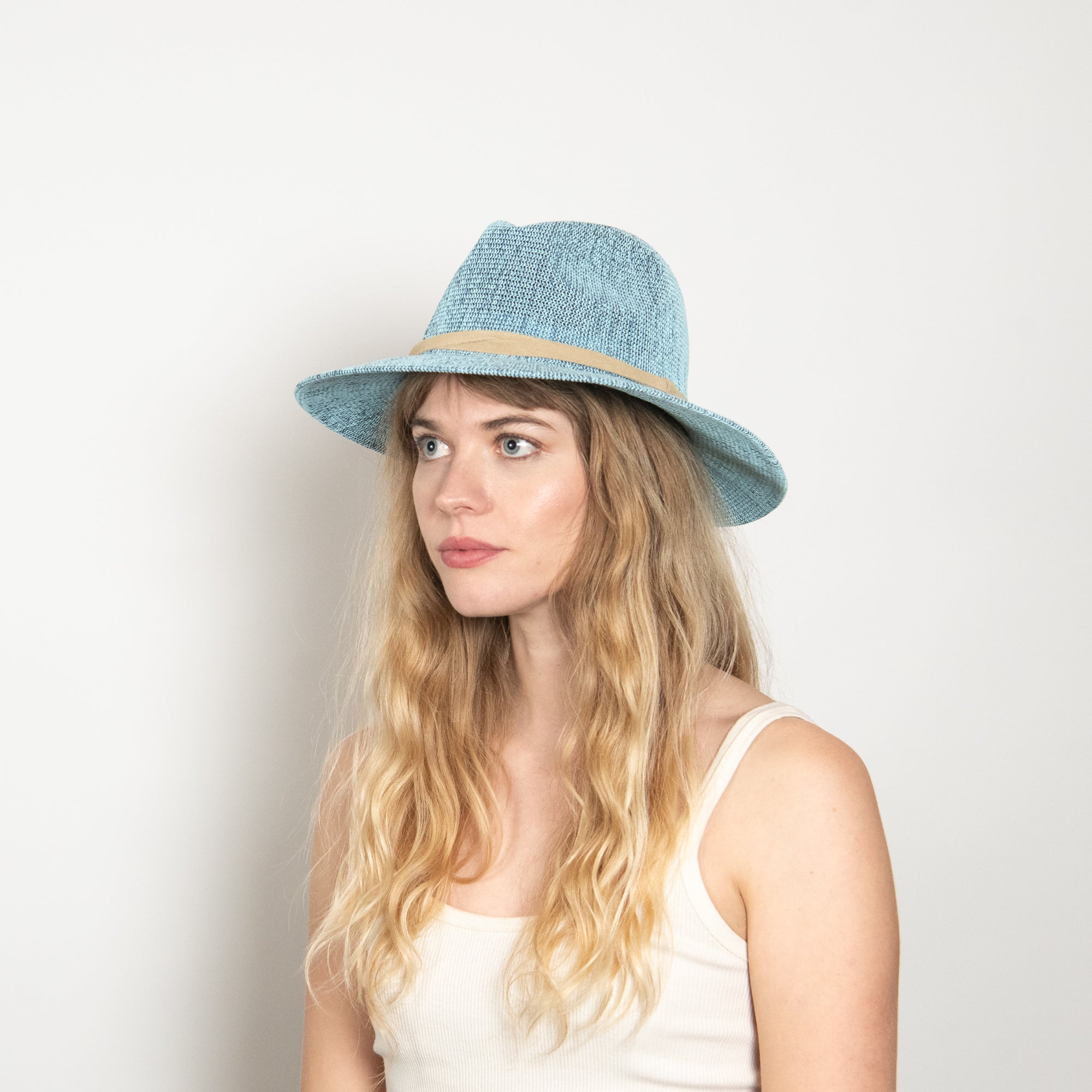 Woman wearing a light blue straw hat against a plain background