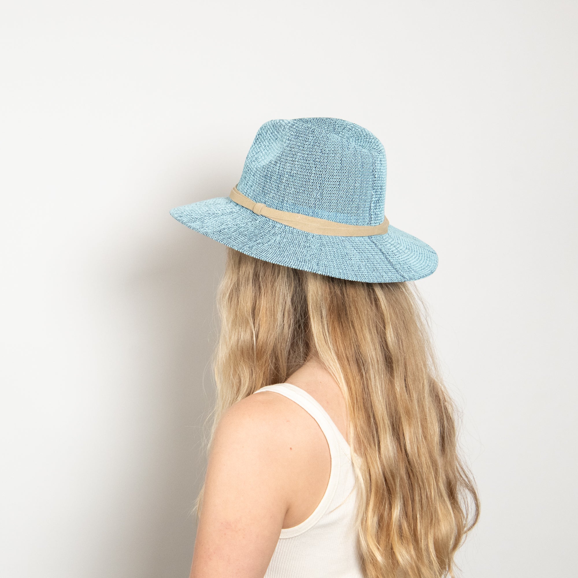 Light blue straw hat with a beige band worn by a person on a plain background