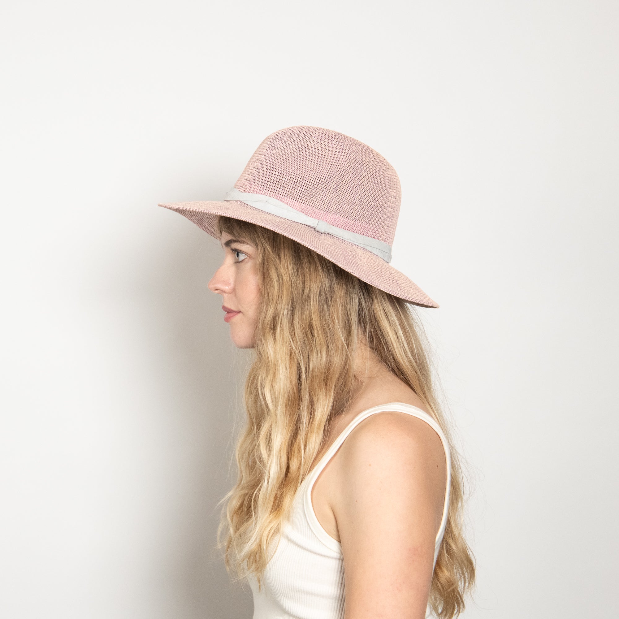 Woman wearing a pink straw hat against a white background