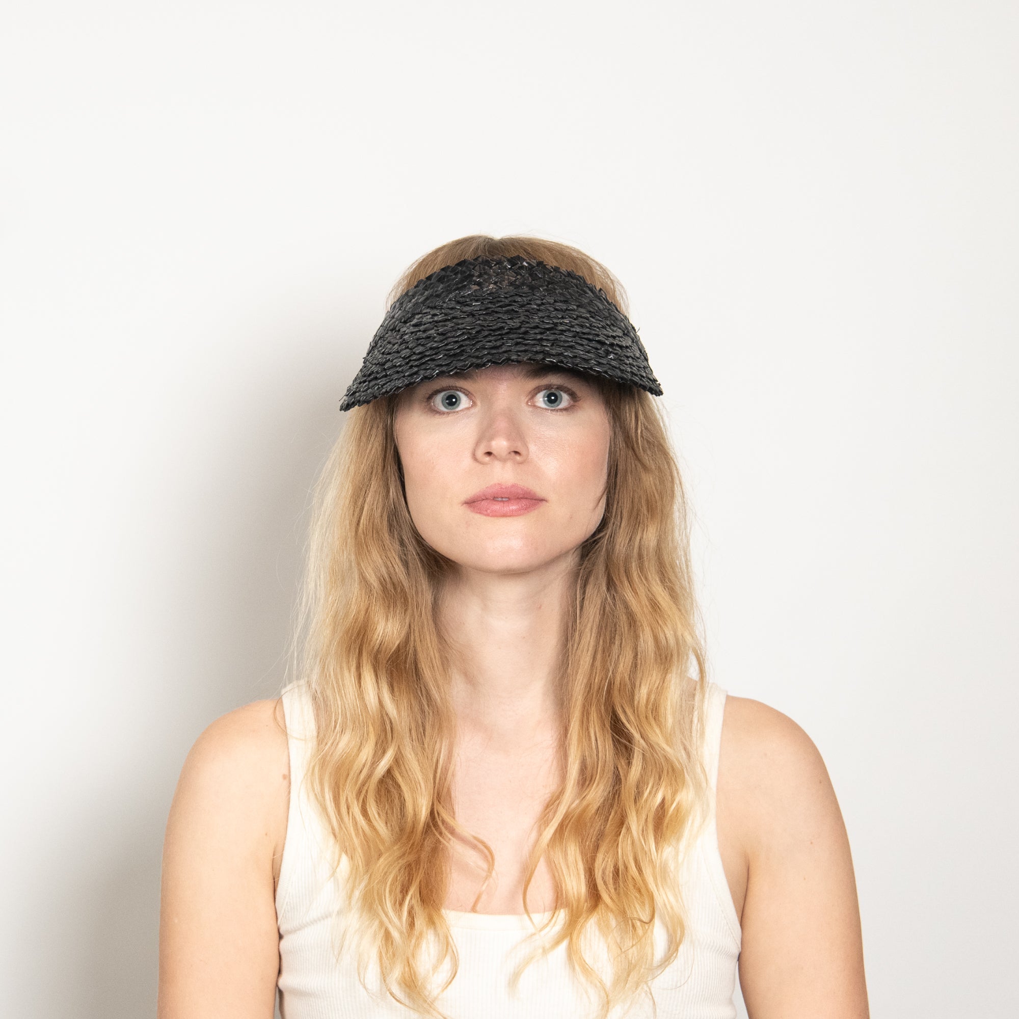 Woman wearing a black visor against a plain background