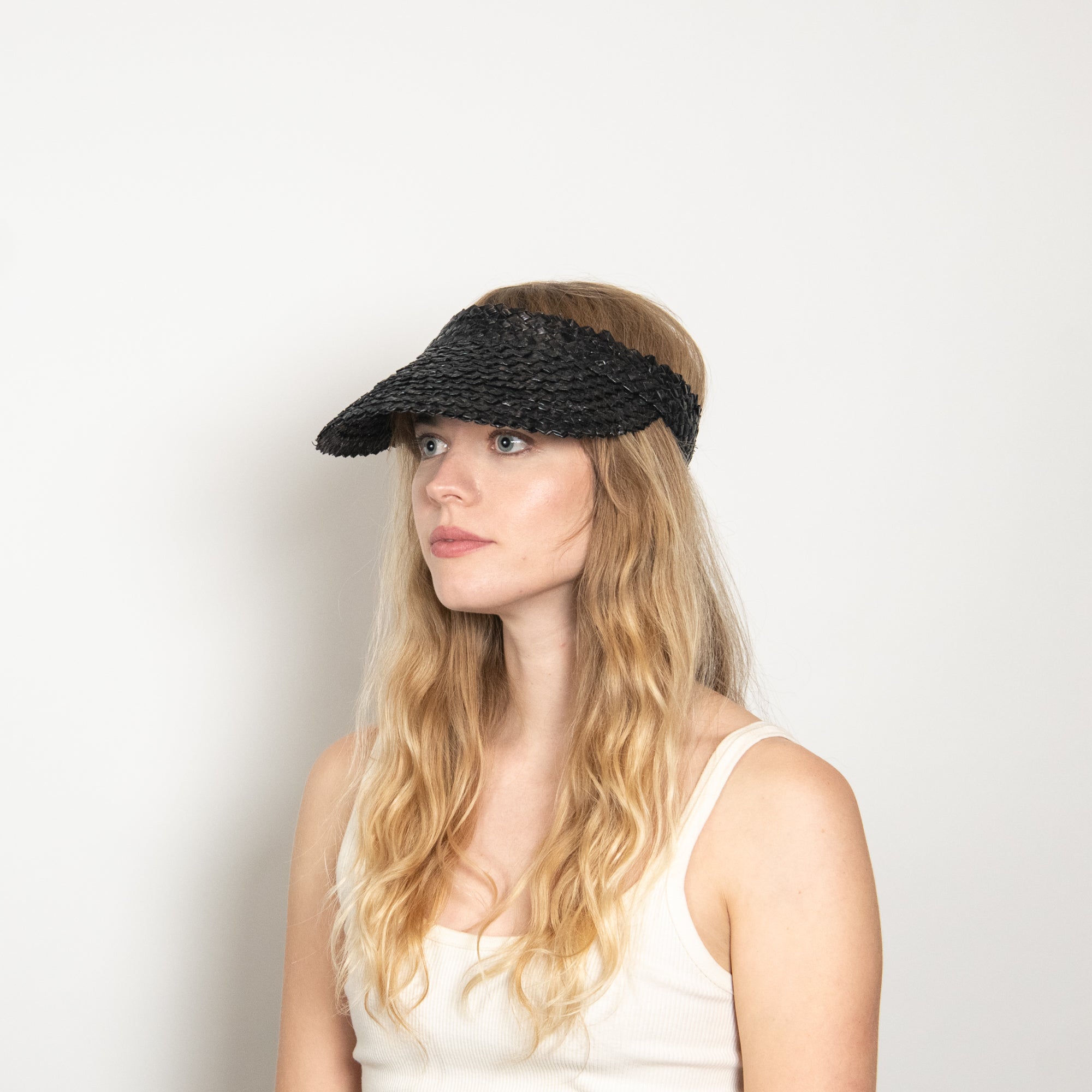 Woman wearing a black visor against a plain background