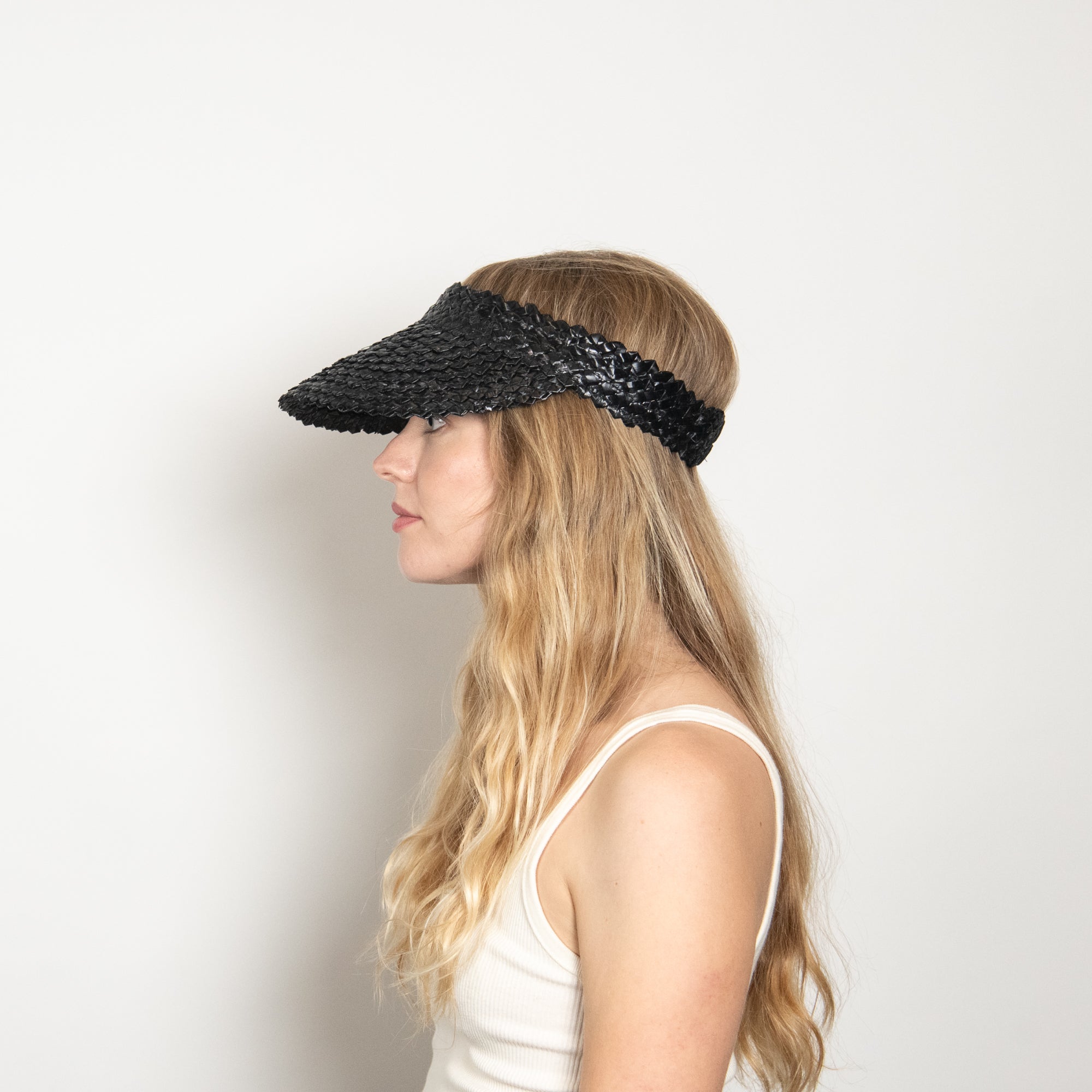 Woman wearing a black visor against a plain background