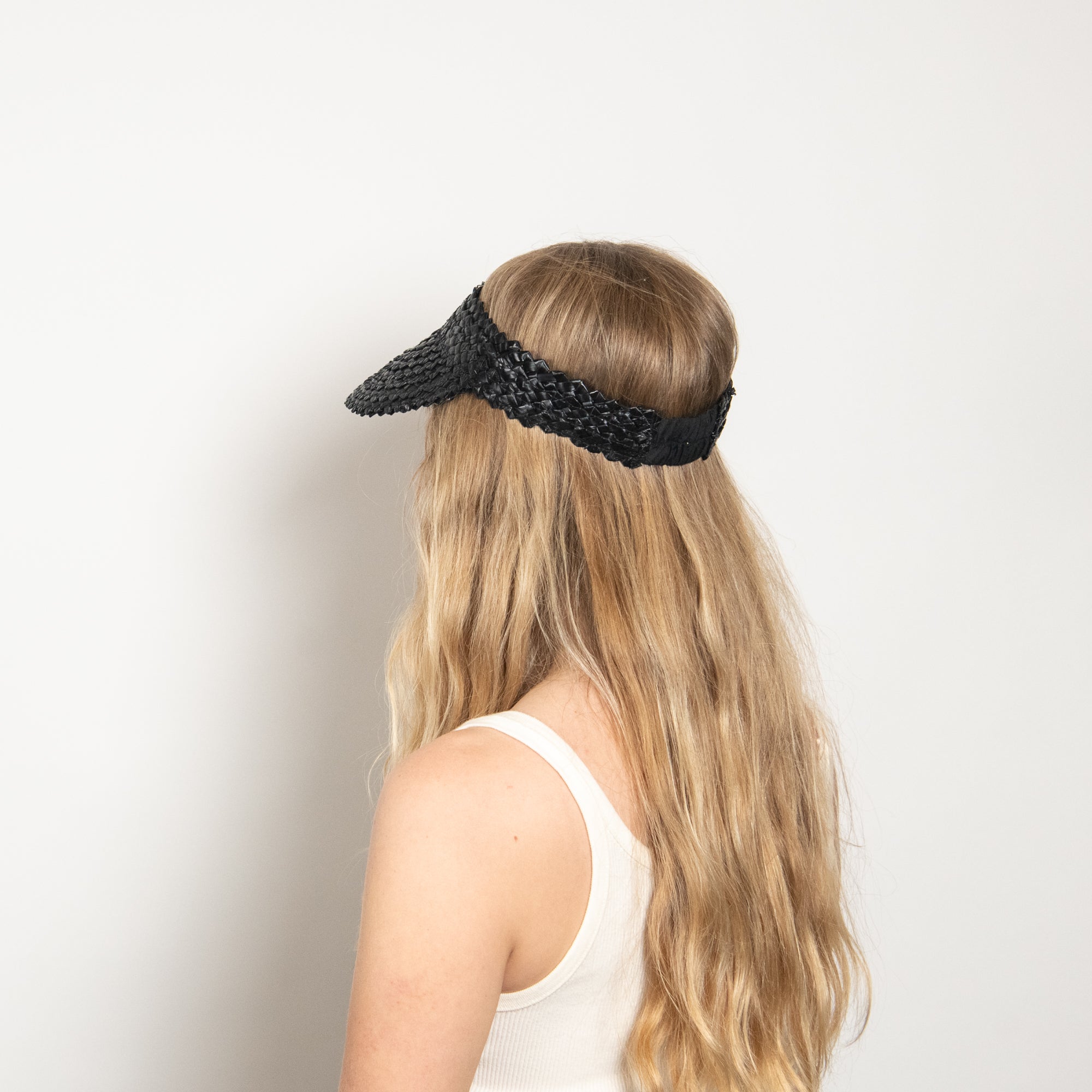 Person wearing a black woven visor against a plain background