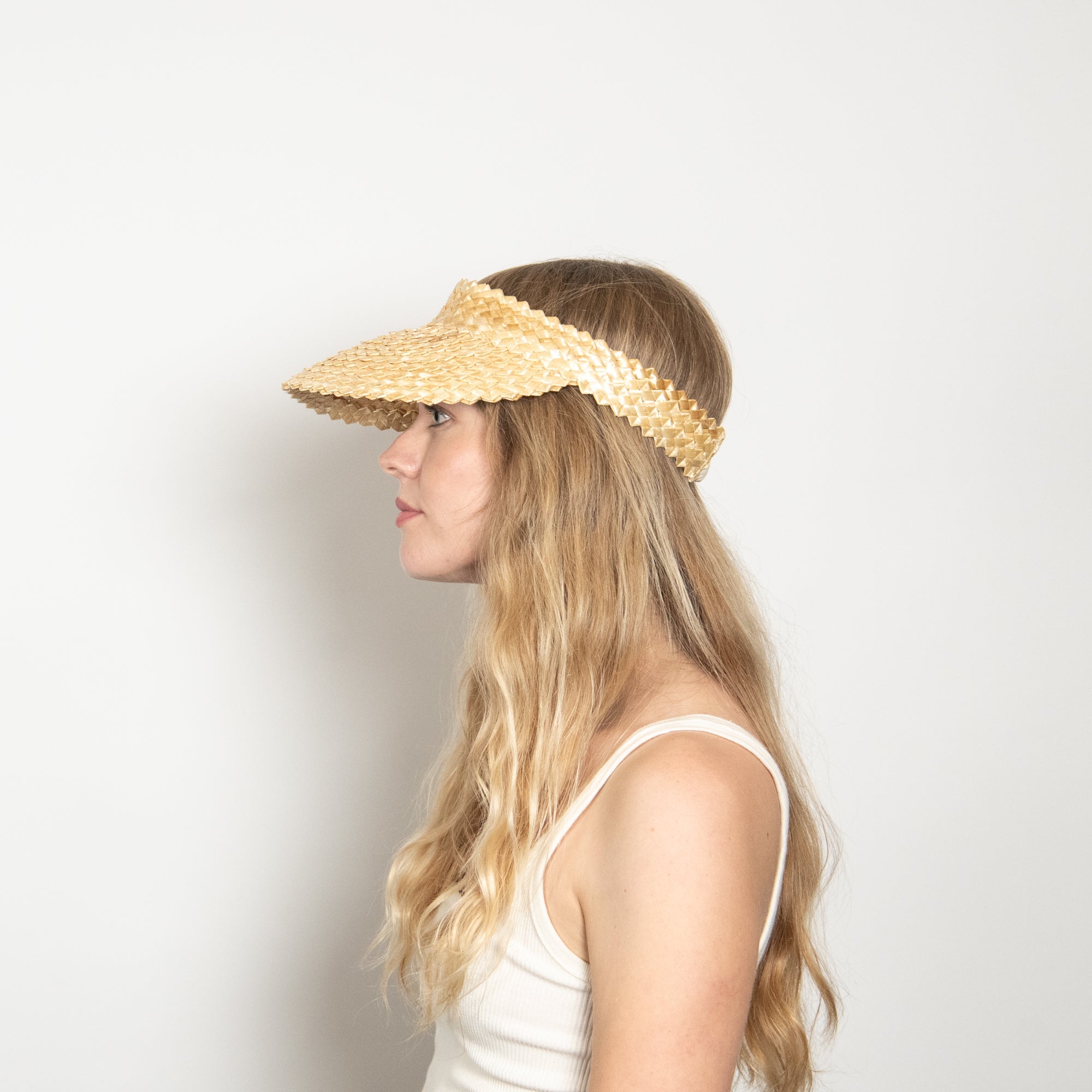Woman wearing a straw visor against a plain background