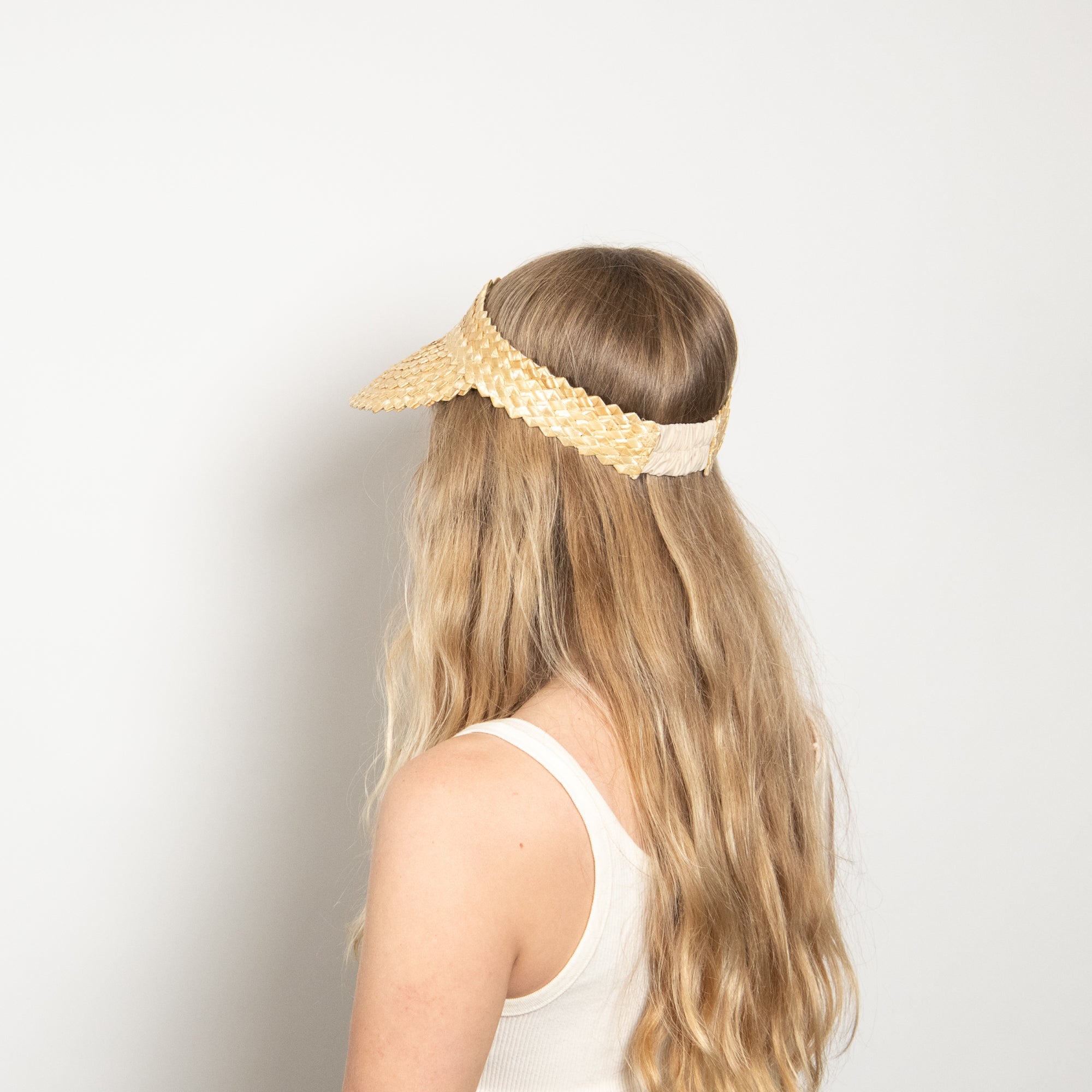 Woman wearing a yellow lace headband on a plain background