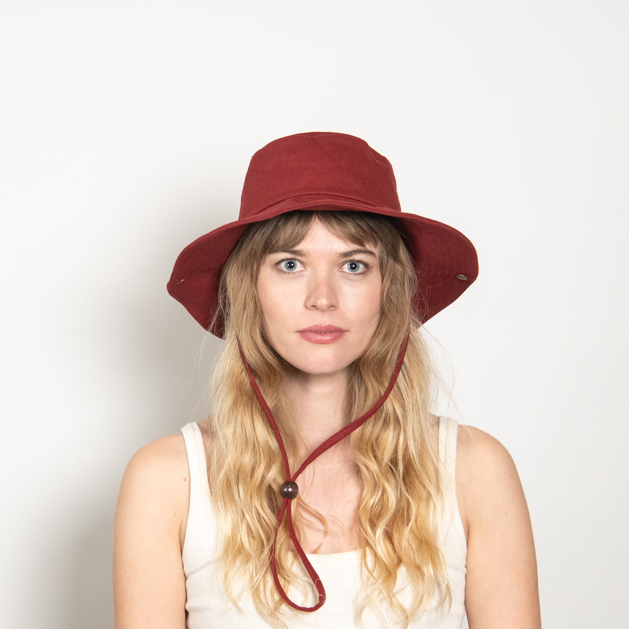 Woman wearing a red bucket hat with a strap on a white background