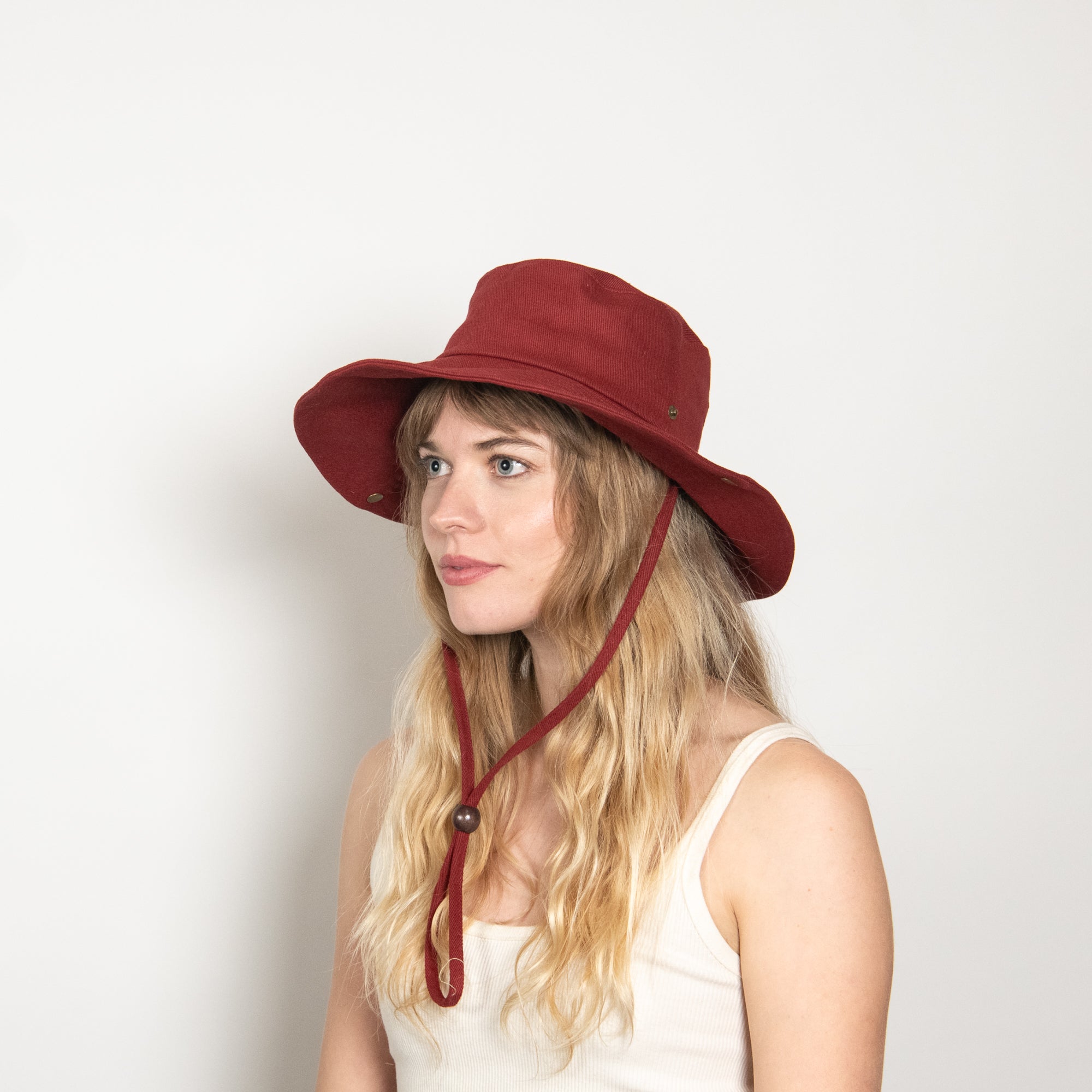 Woman wearing a red bucket hat with a strap on a white background