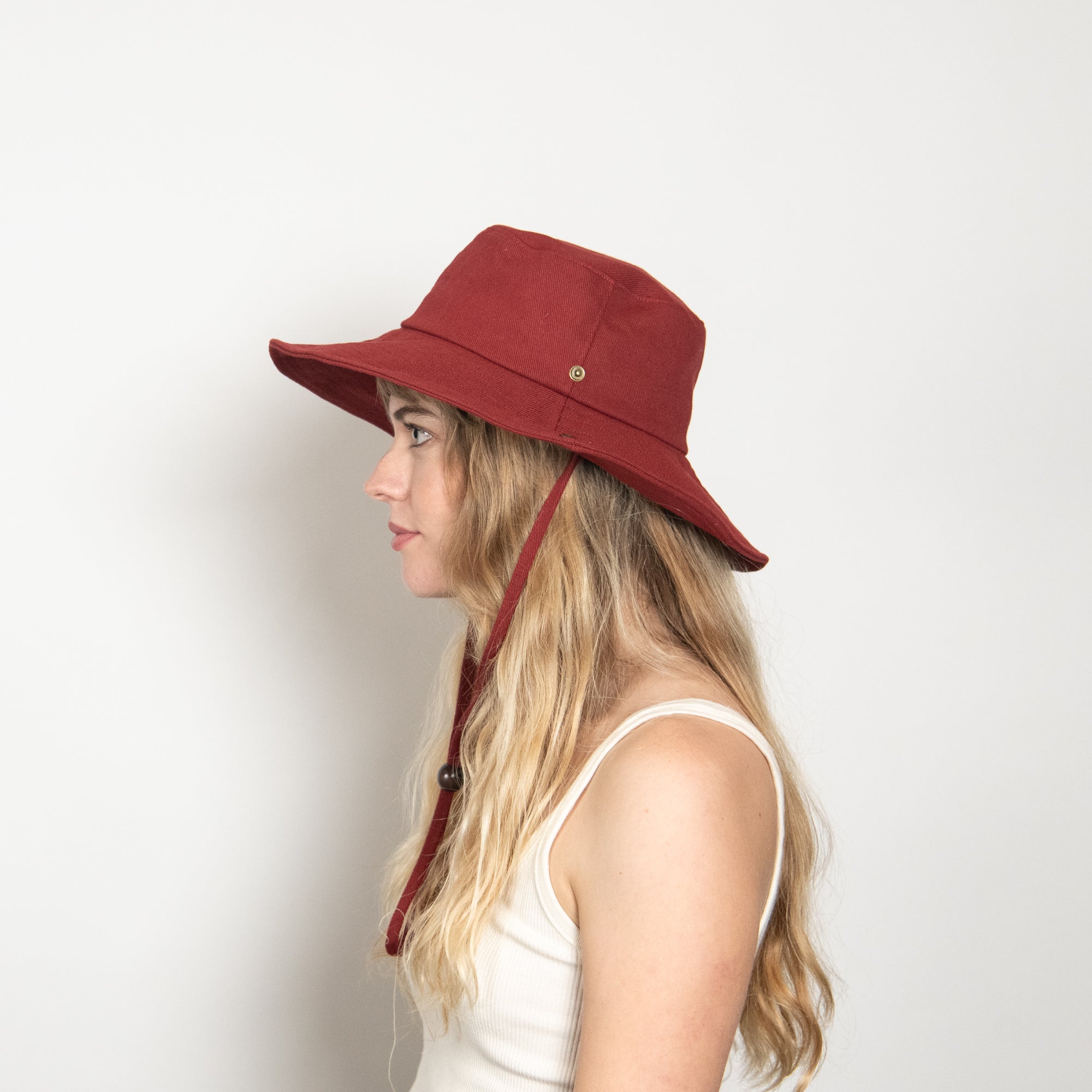 Woman wearing a red bucket hat on a plain background