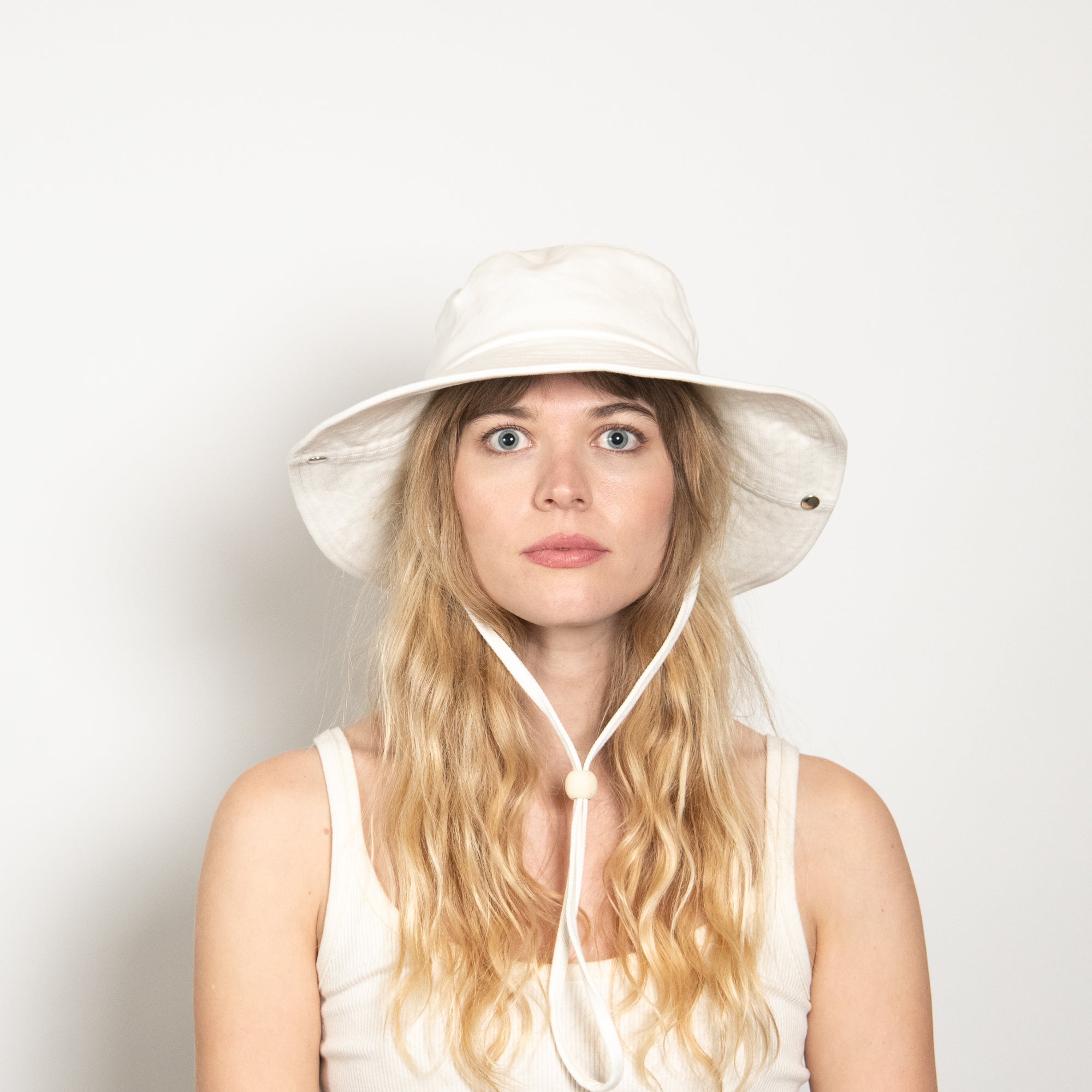 Woman wearing a white bucket hat against a light background