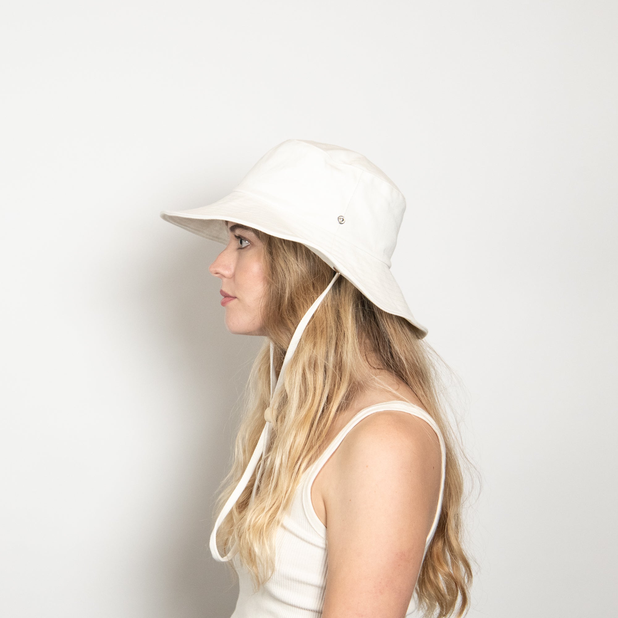 Woman wearing a white bucket hat on a plain background