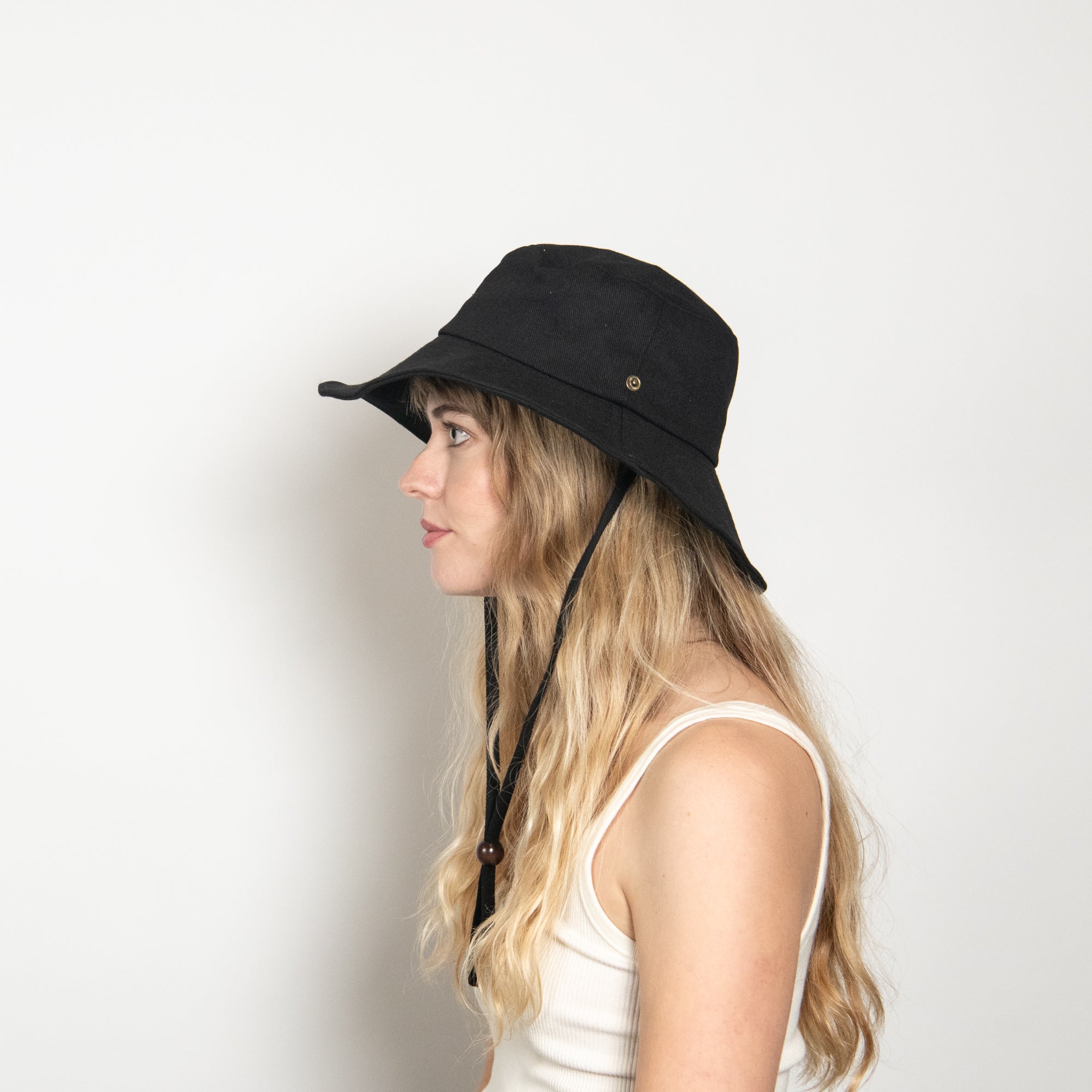 Woman wearing a black bucket hat with a strap on a white background