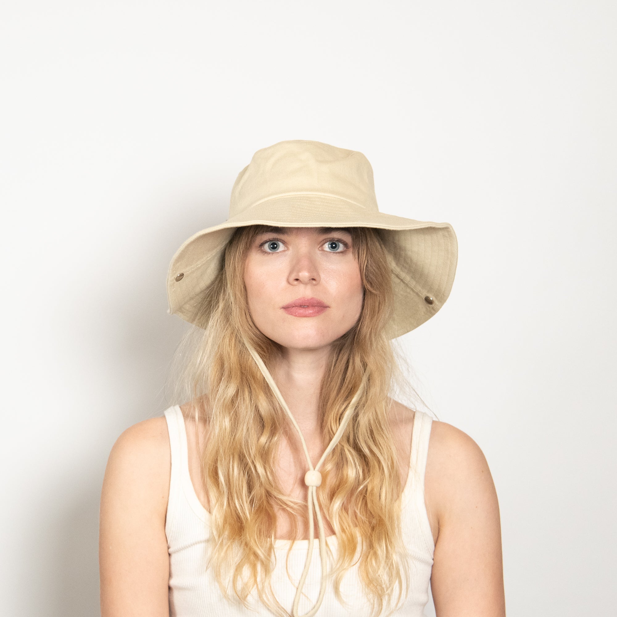 Woman wearing a beige sun hat with a white background