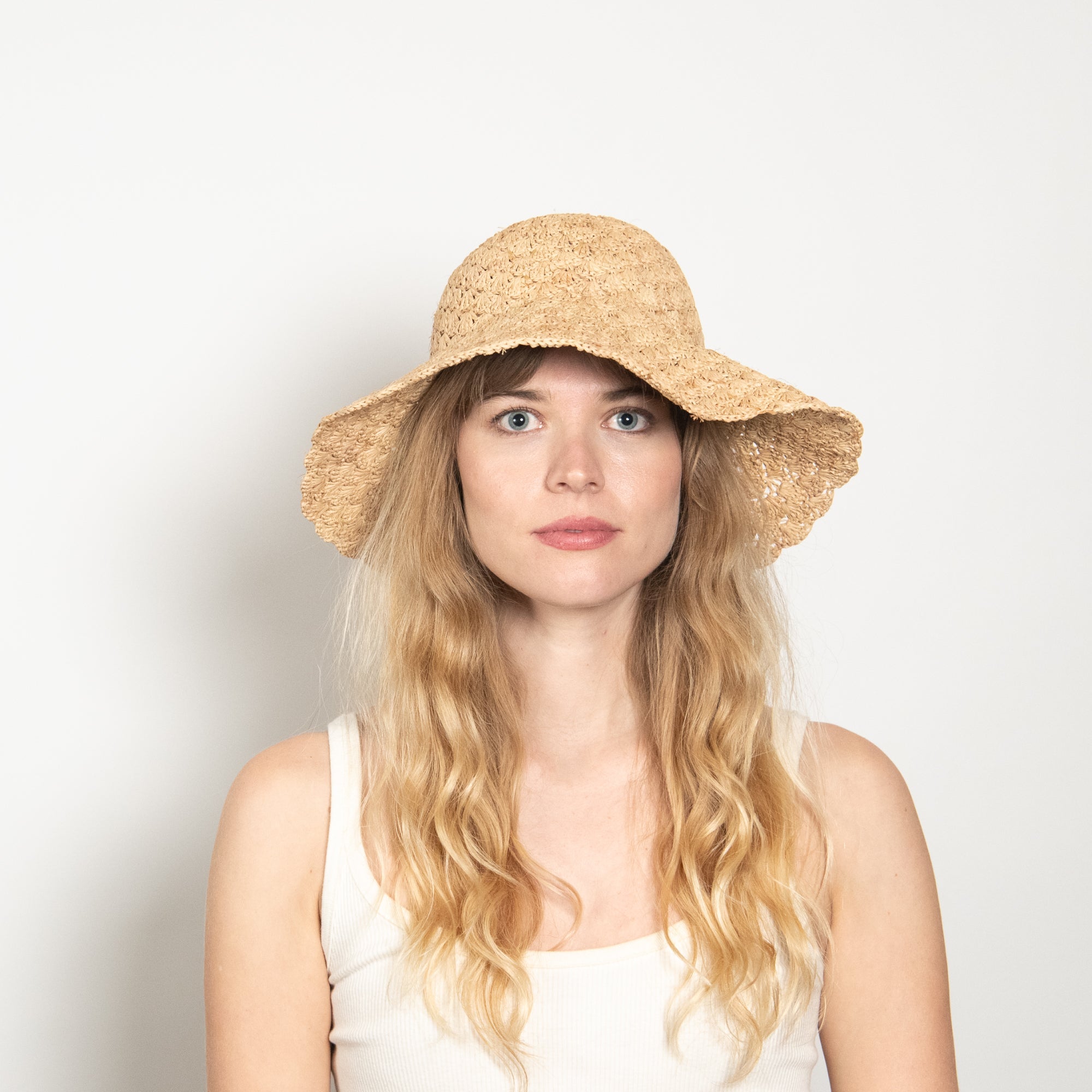 Woman wearing a straw hat against a plain background