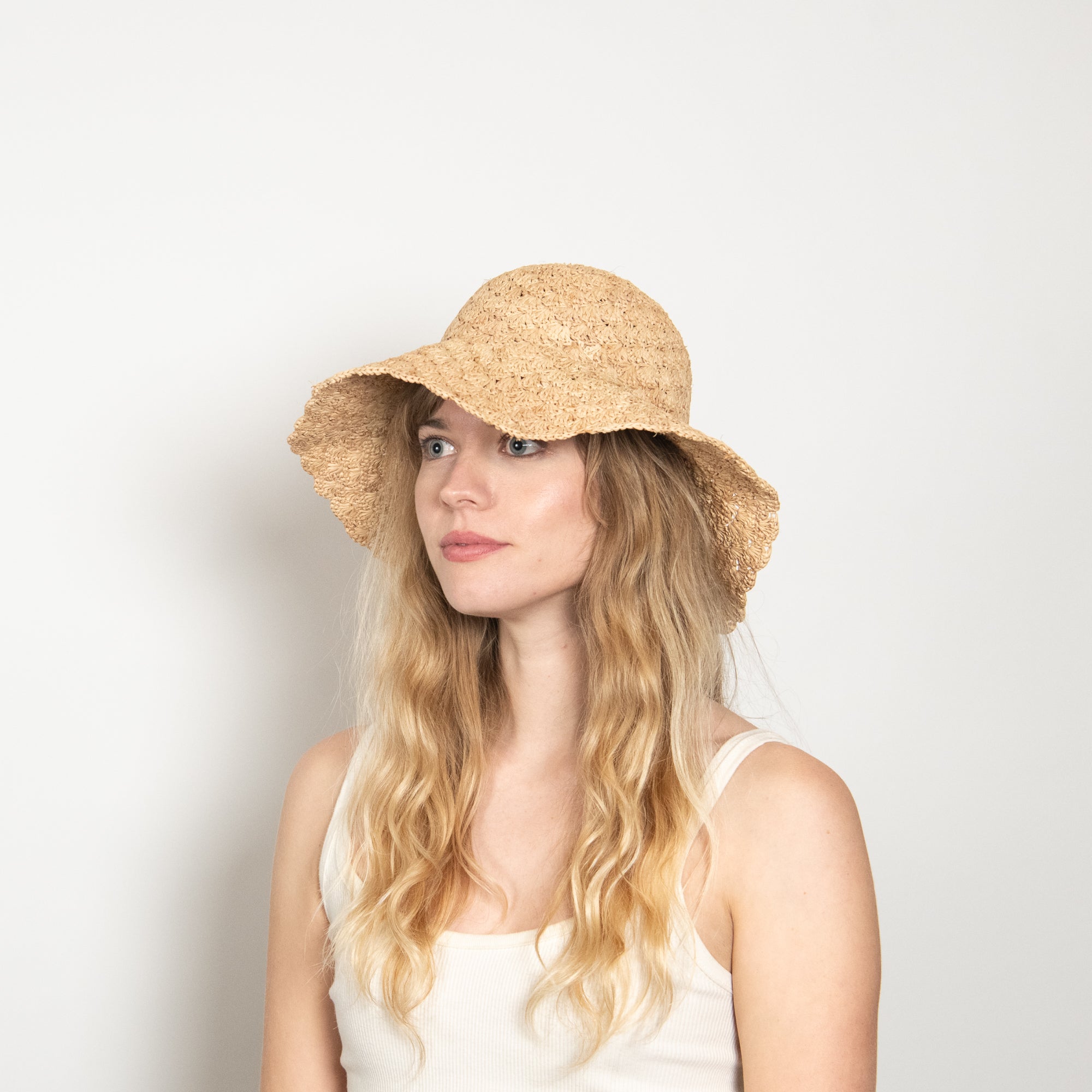 Woman wearing a straw hat against a plain background