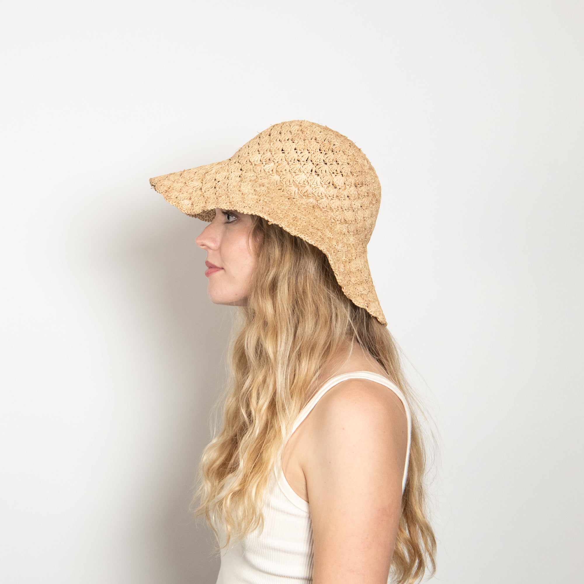 Woman wearing a straw hat against a plain background