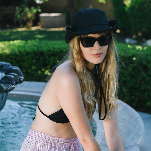 Woman in black bikini top and cap with sunglasses outdoors