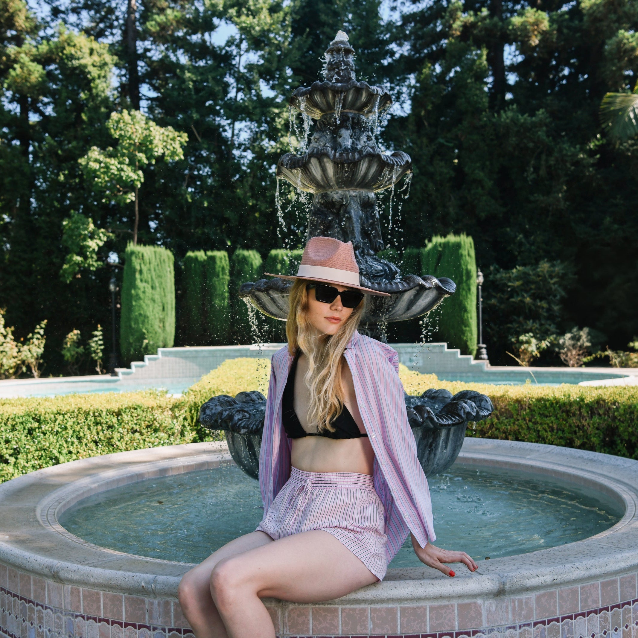 Woman sitting on a fountain in a garden setting