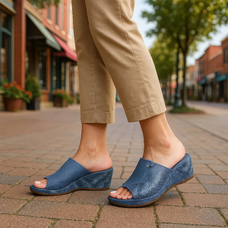 Person wearing blue open-toe shoes on a sidewalk with a blurred street background