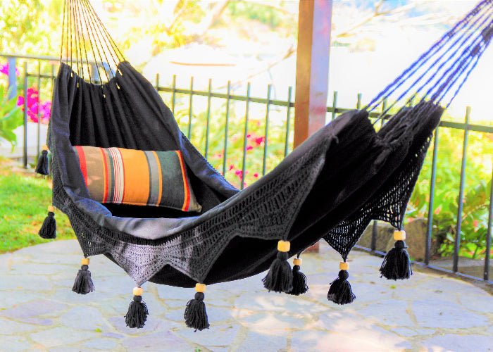 Black hammock with colorful pillow in a garden setting