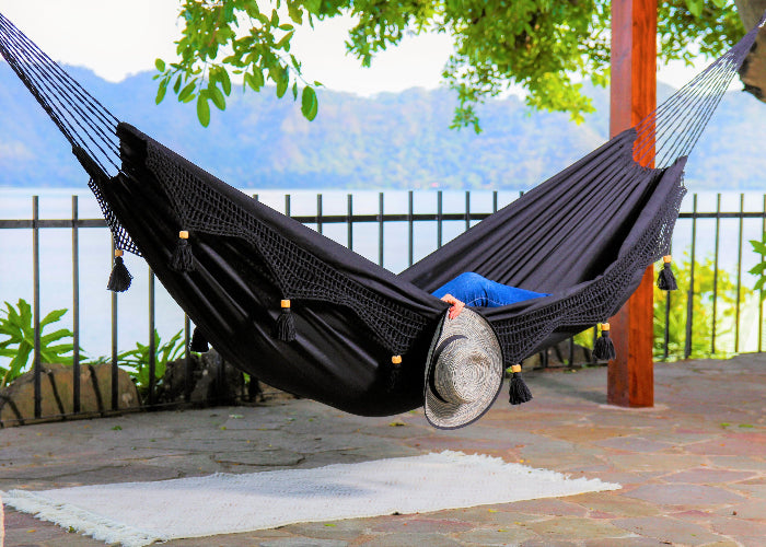 Person relaxing in a black hammock with a scenic background