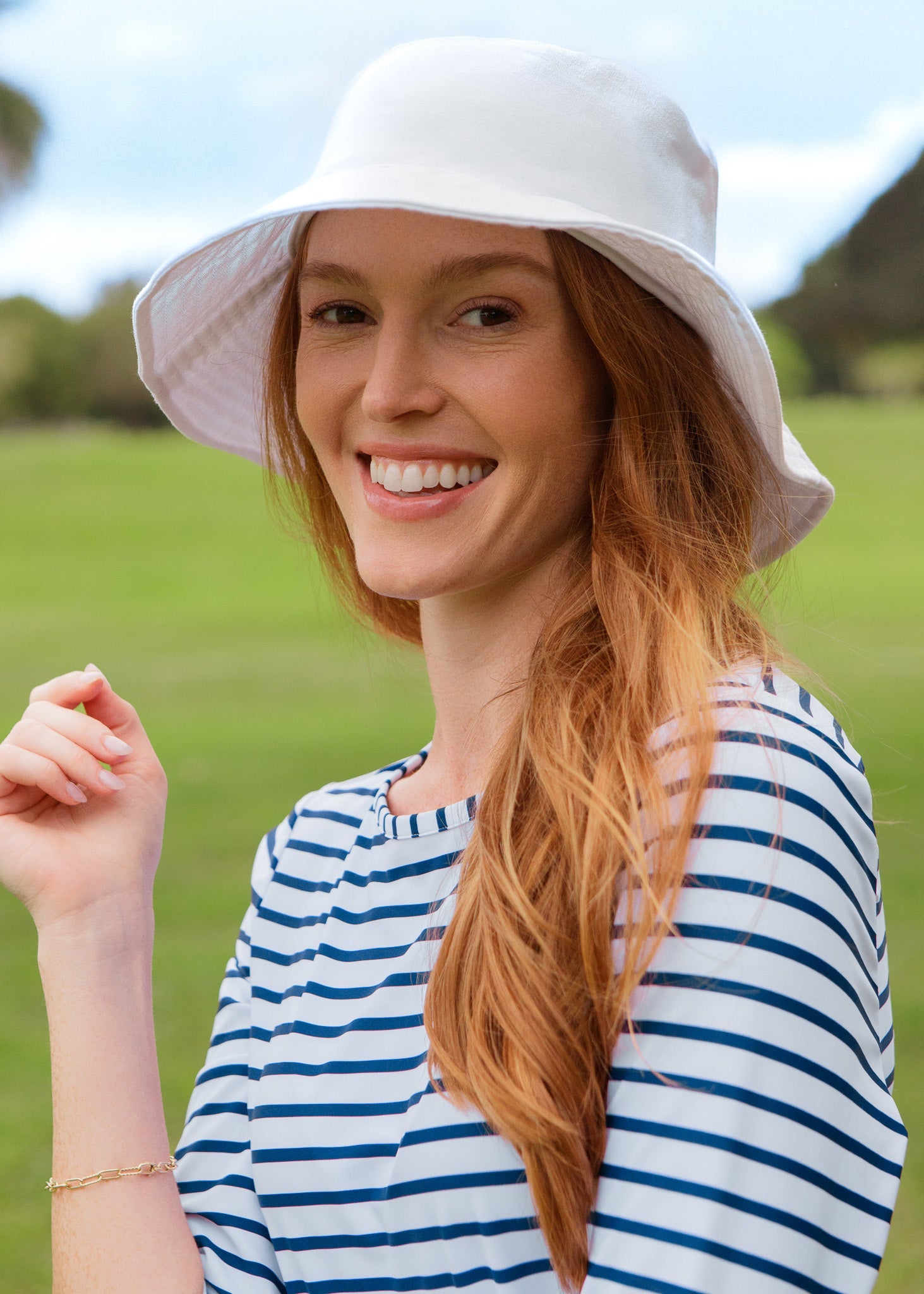 Woman wearing a white bucket hat and striped shirt in an outdoor setting