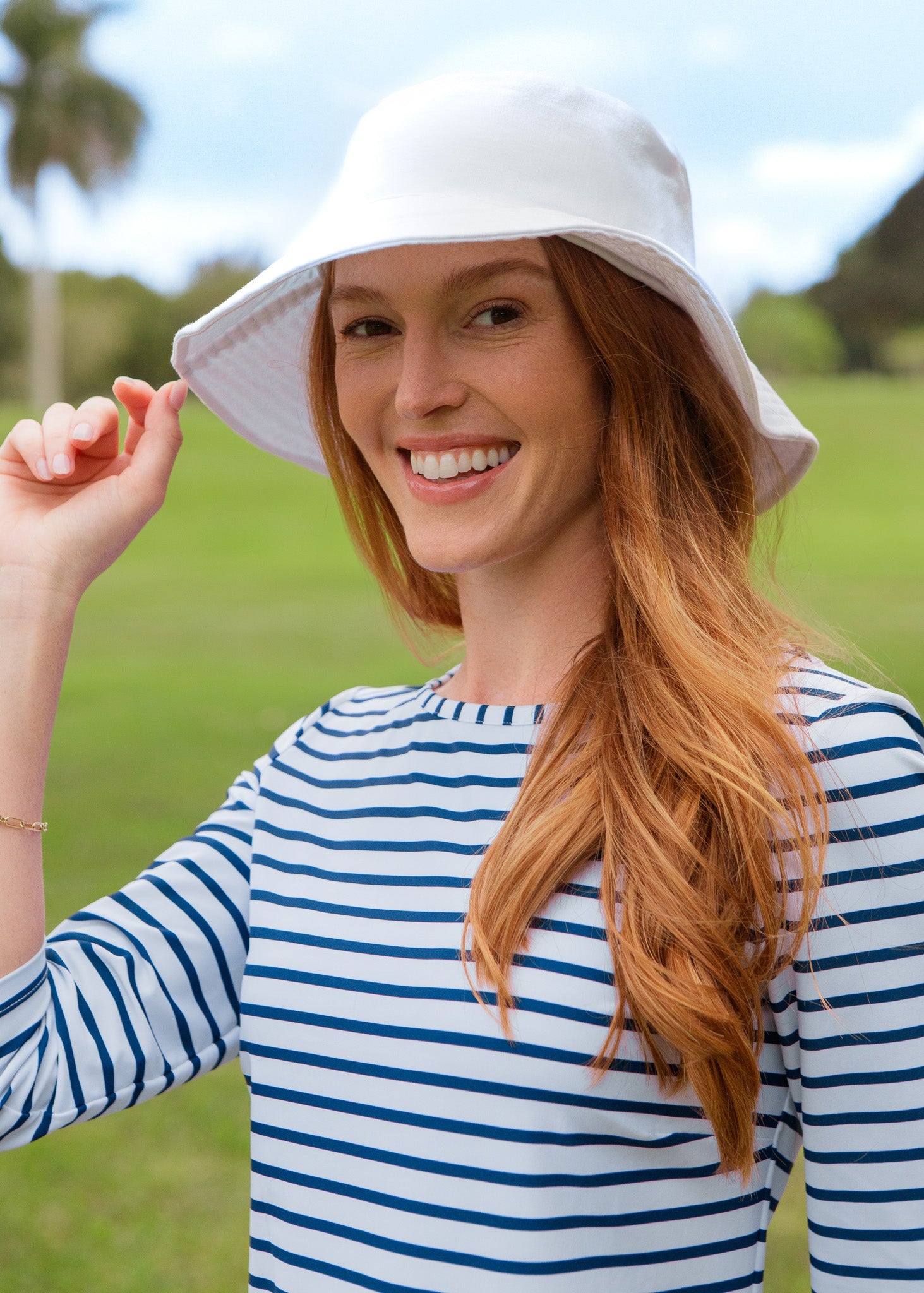 Woman wearing a white bucket hat and striped shirt outdoors