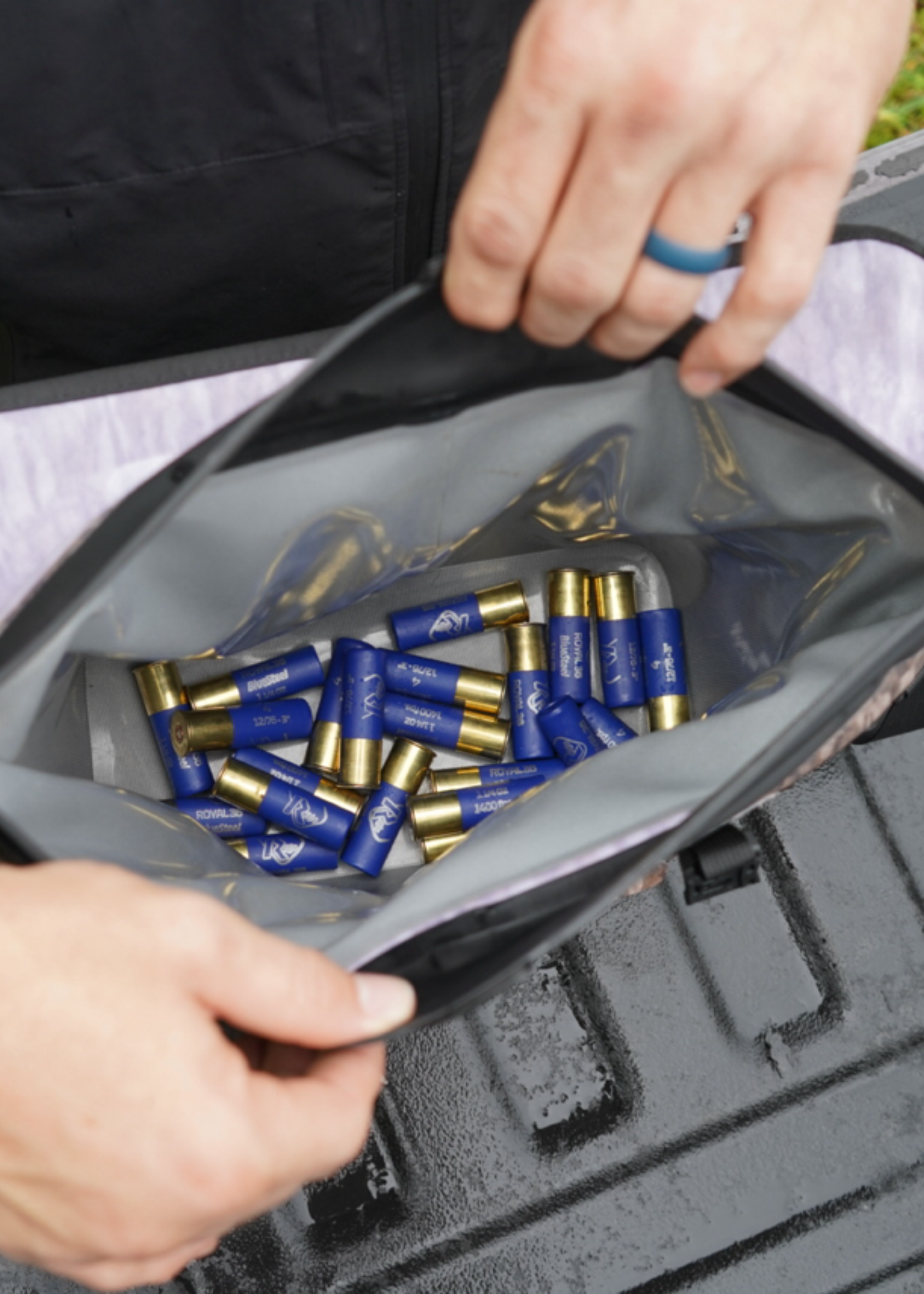 Person opening a bag filled with blue and gold shotgun shells.
