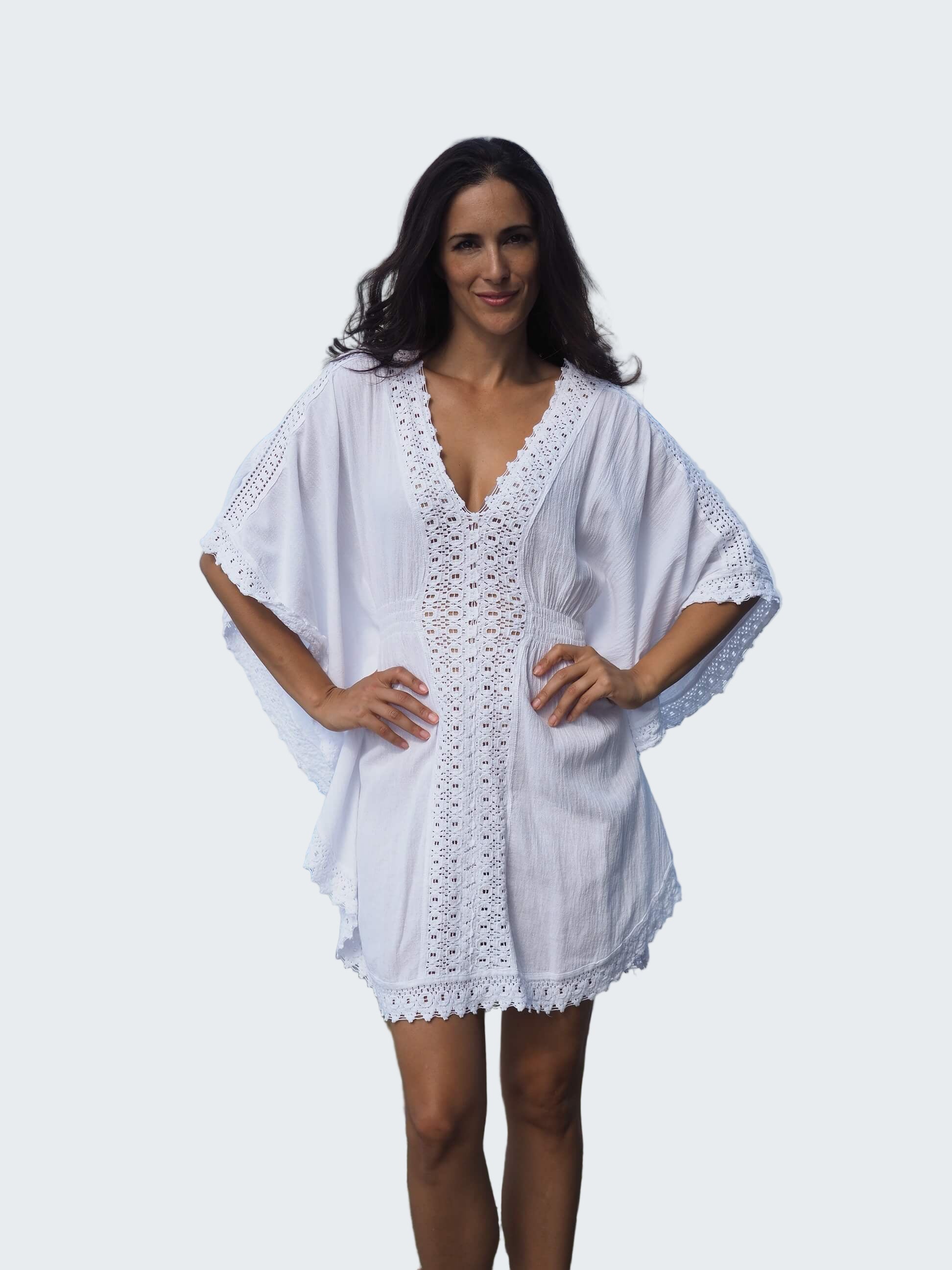 Woman wearing a white lace dress standing by a waterfront with a city skyline in the background