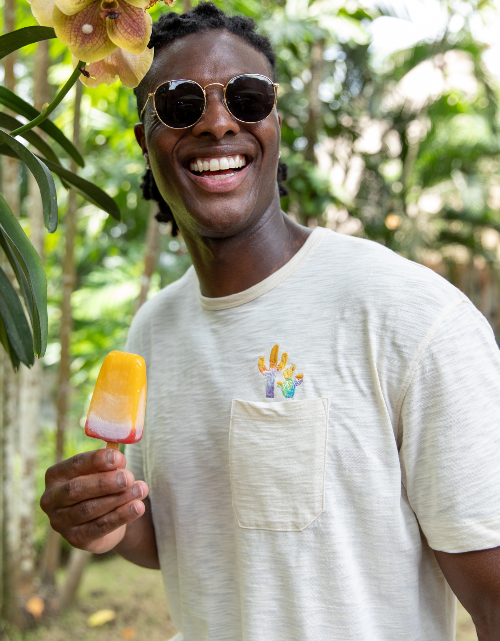 Man holding a popsicle with a tropical background