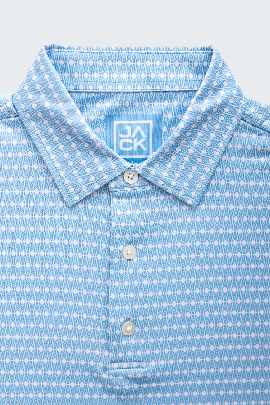 Close-up of a blue patterned shirt with a brand label on a white background