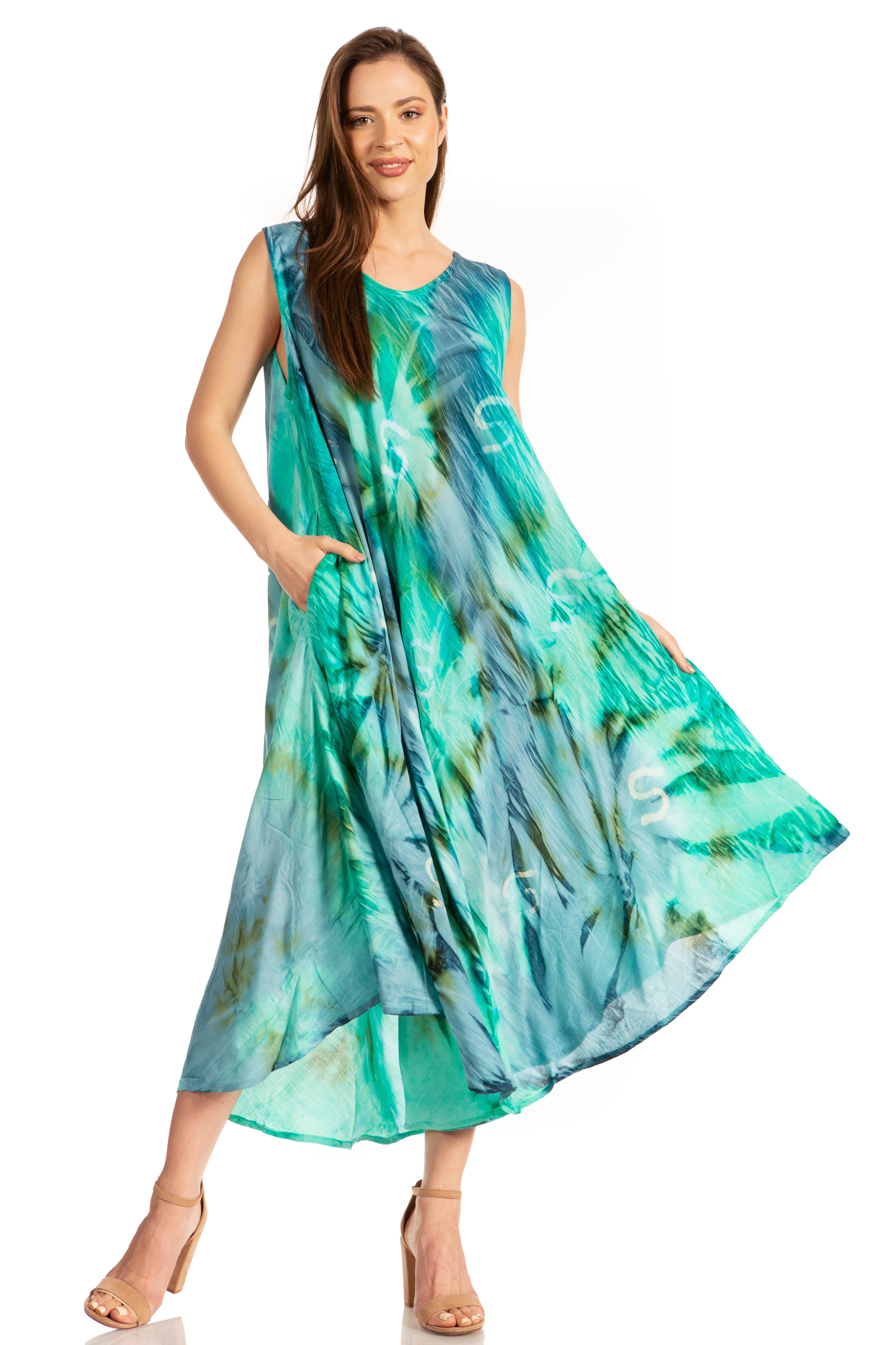 Woman wearing a sleeveless, long, green and blue patterned dress on a white background