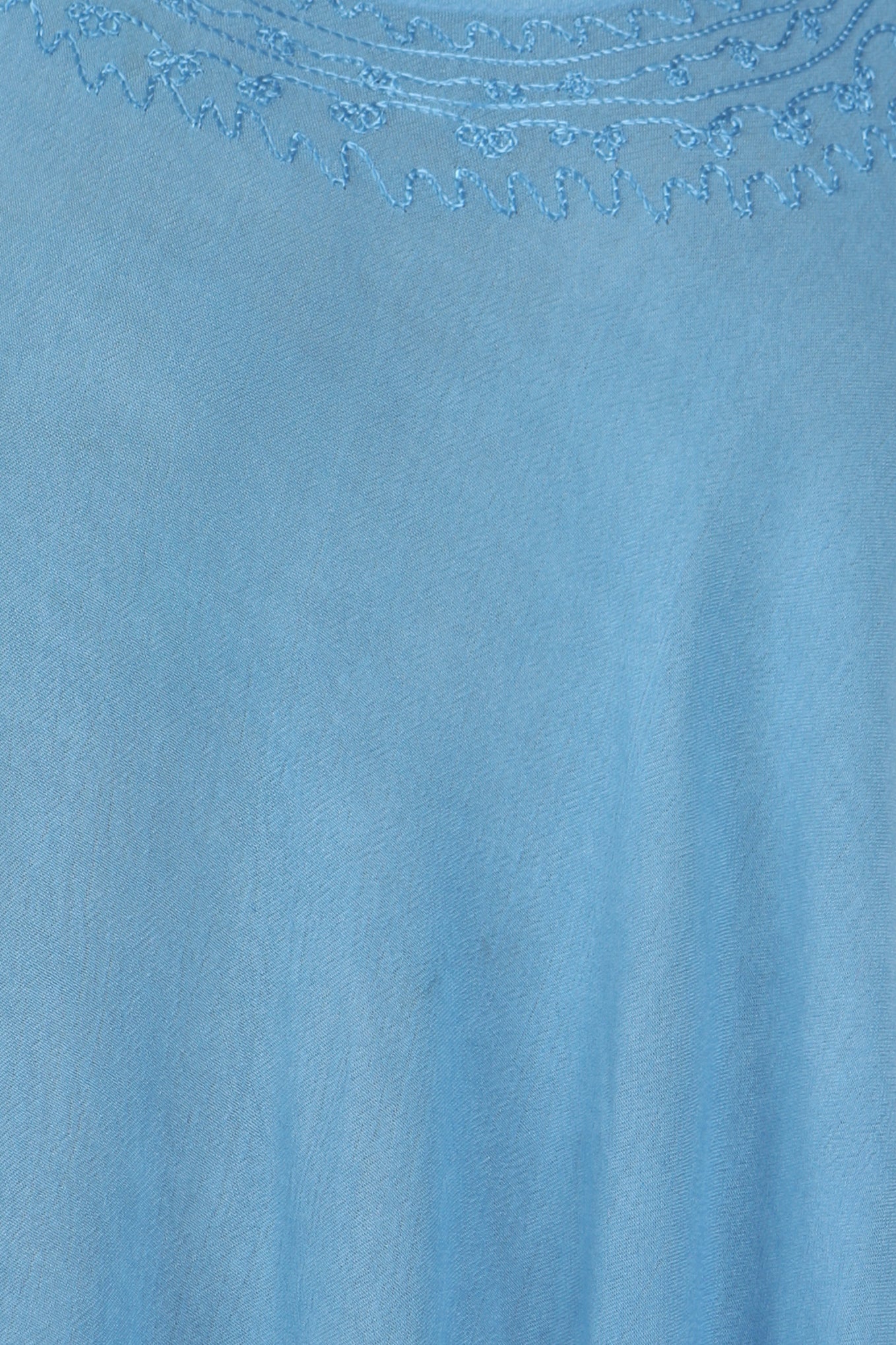 Close-up of a light blue fabric with intricate embroidery at the neckline.