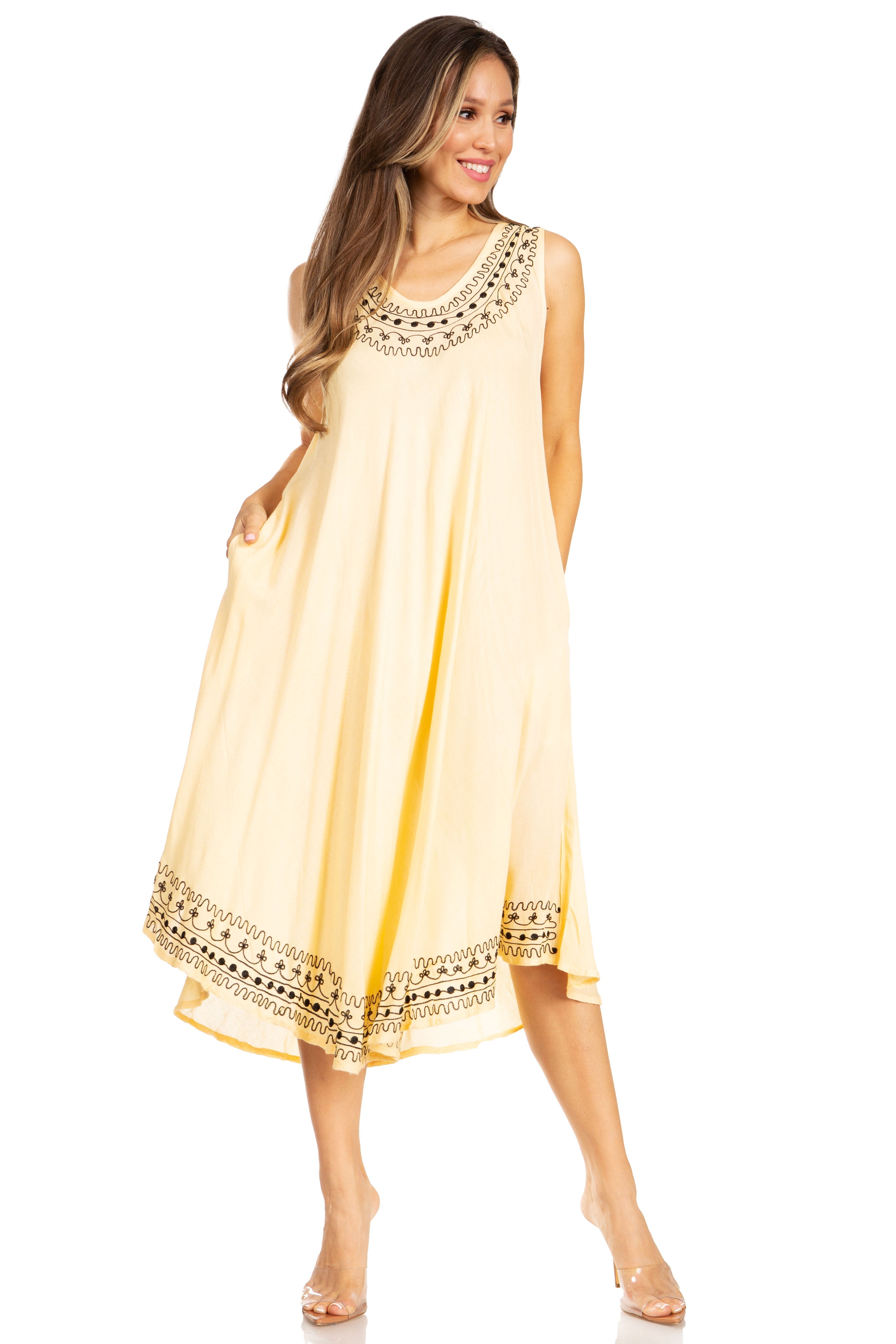 Woman wearing a beige sleeveless dress with black embroidery on a white background
