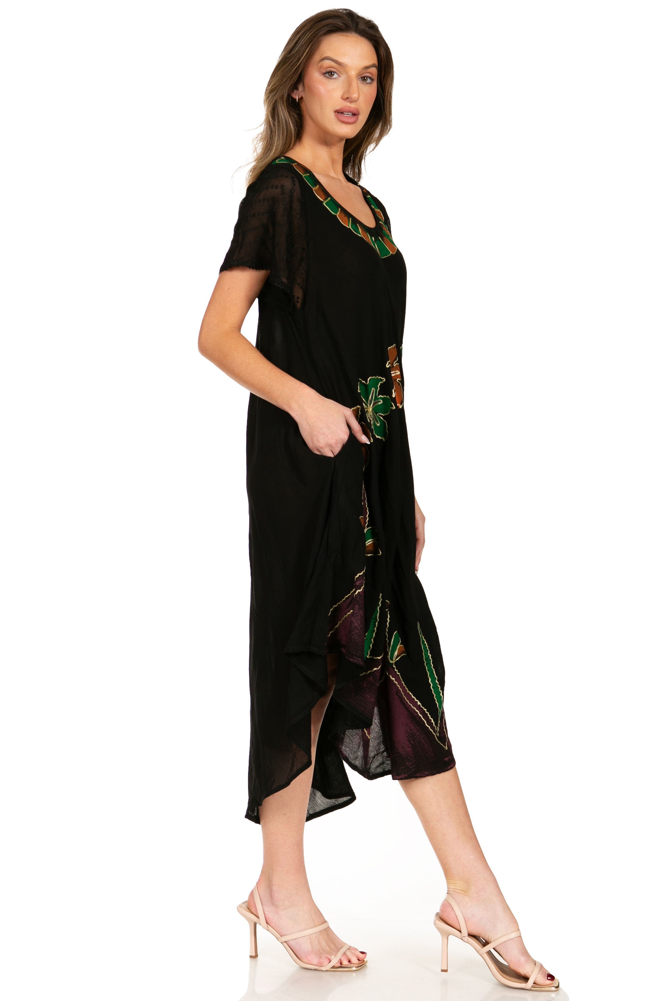 Woman wearing a black dress with green floral patterns on a white background
