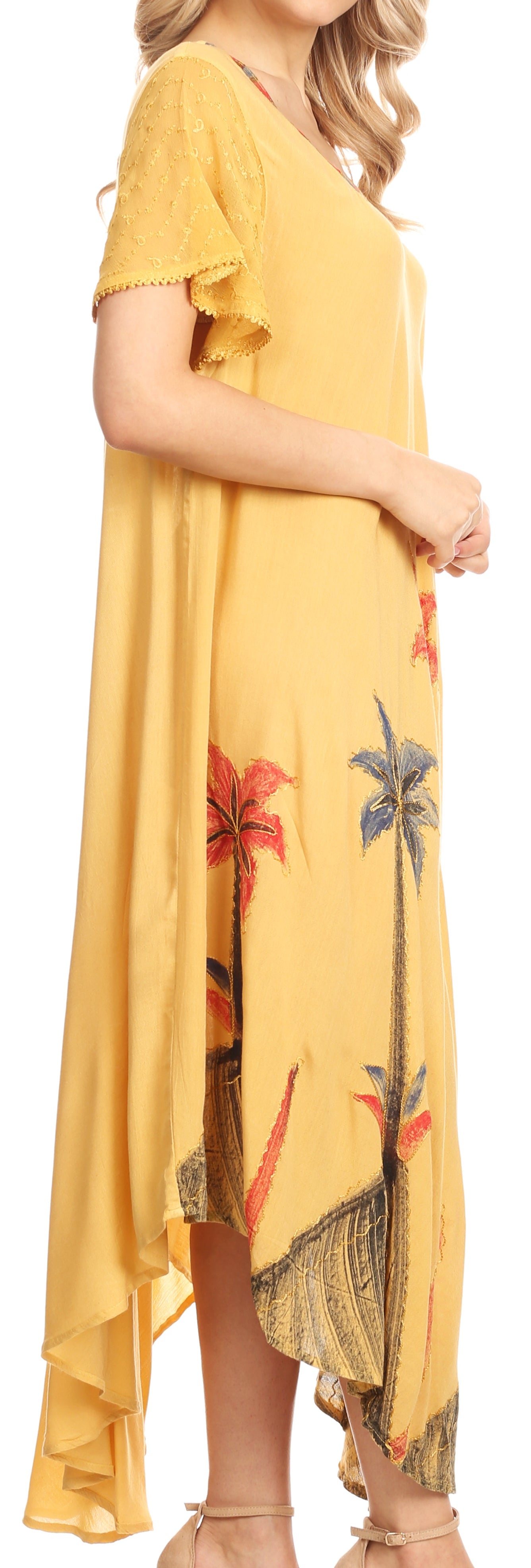 Woman wearing a yellow dress with floral patterns, standing against a neutral background.