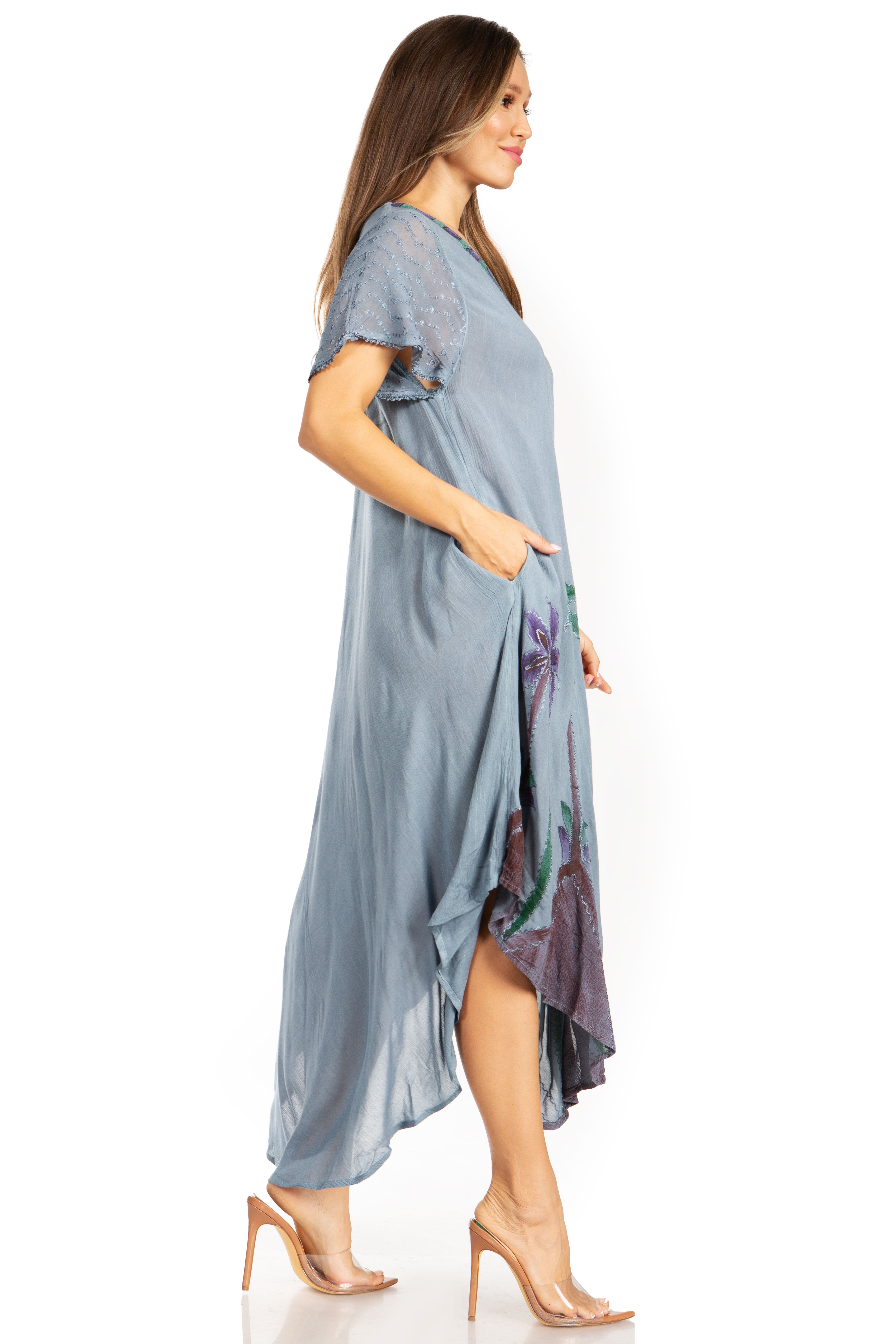 Woman wearing a long, light blue dress with floral patterns on a white background