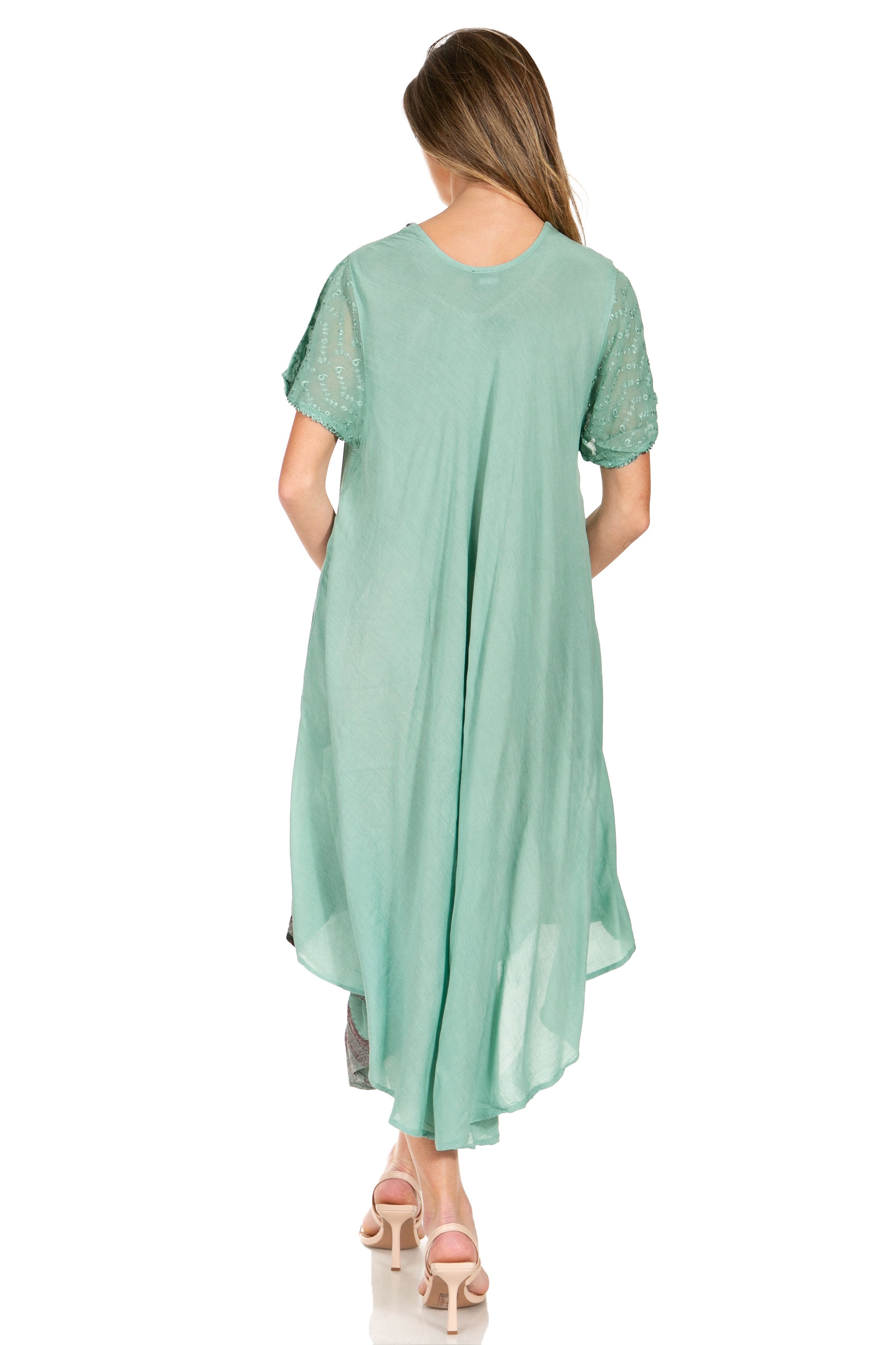 Woman wearing a light green dress with sheer sleeves on a white background