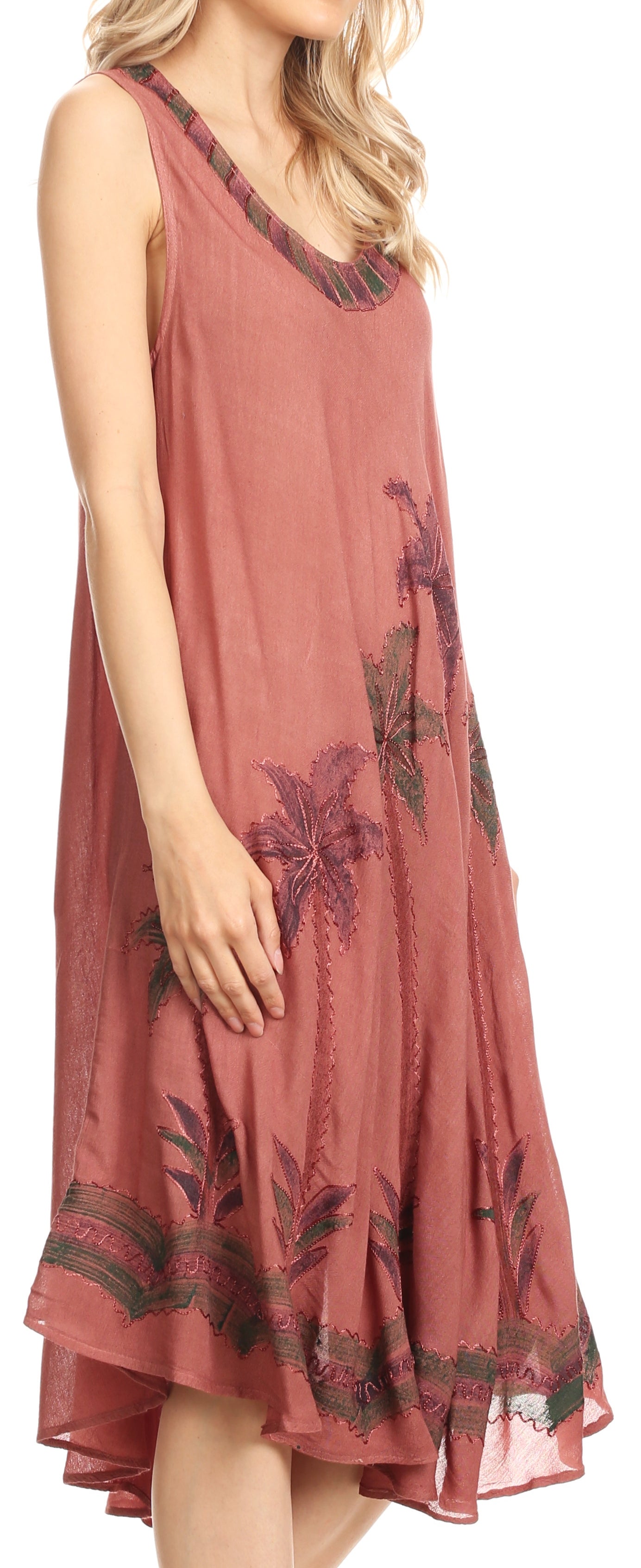 Woman wearing a sleeveless dress with floral patterns on a plain background