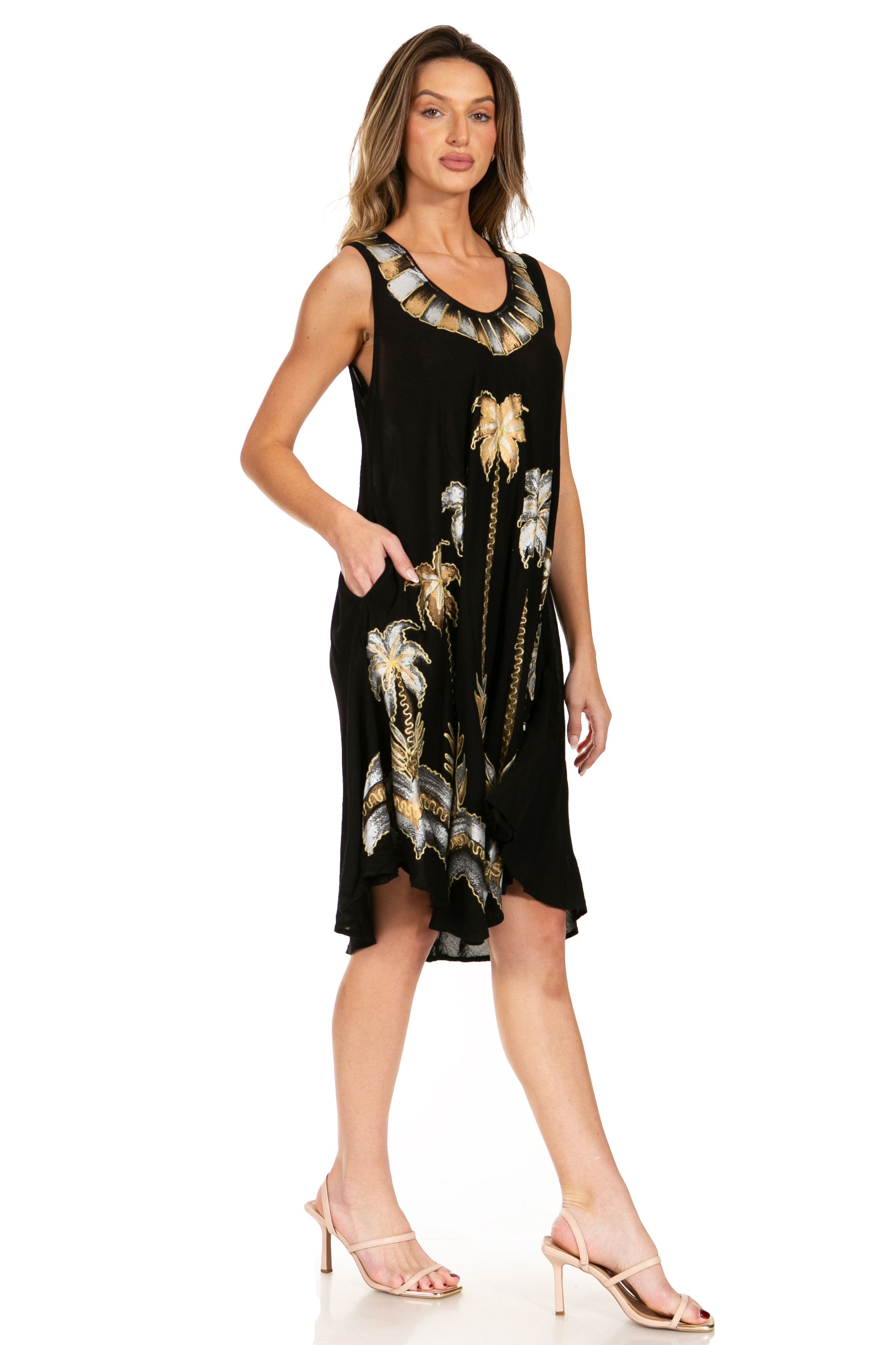 Woman wearing a black sleeveless dress with gold feather patterns on a white background