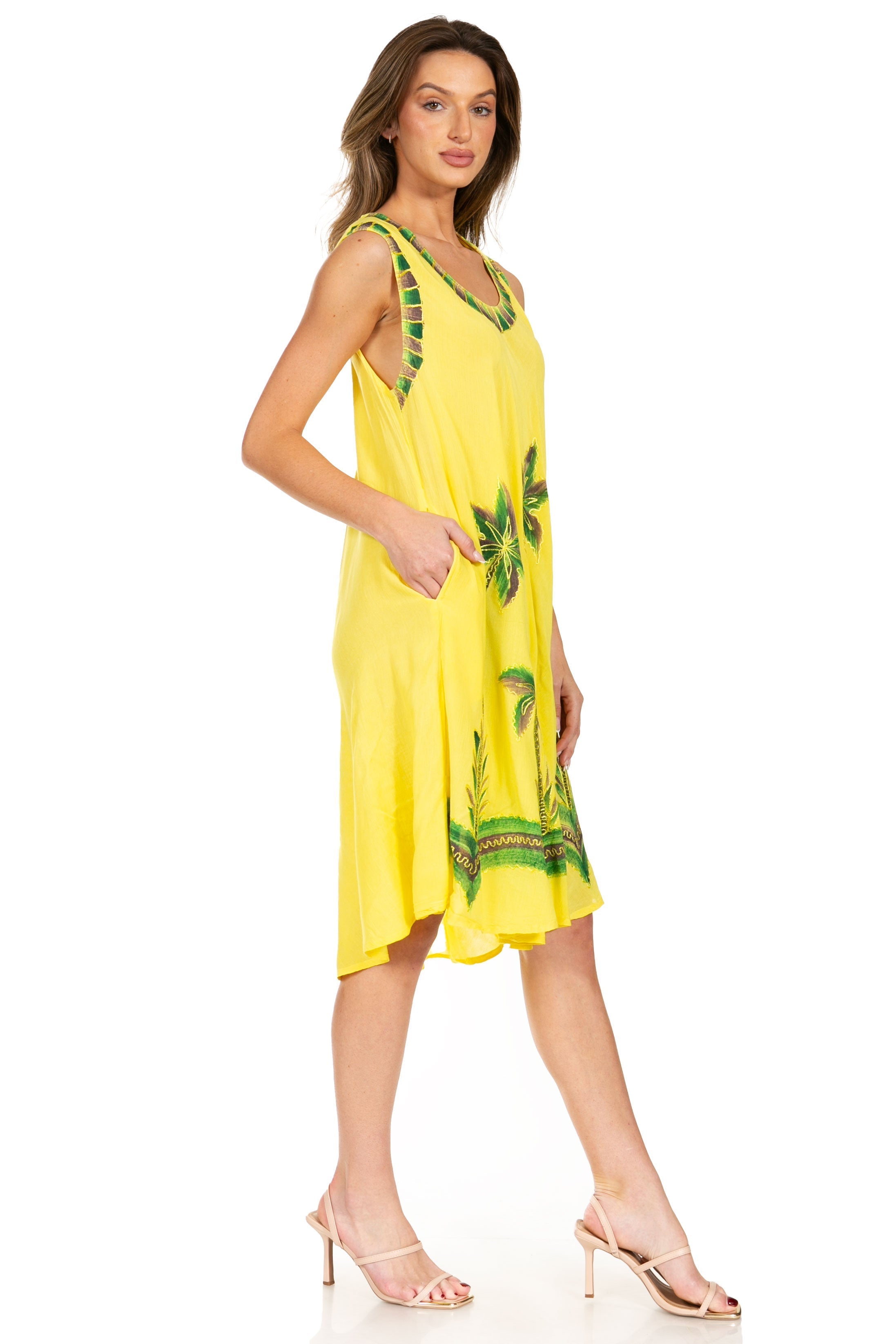 Woman wearing a yellow dress with green leaf patterns on a white background