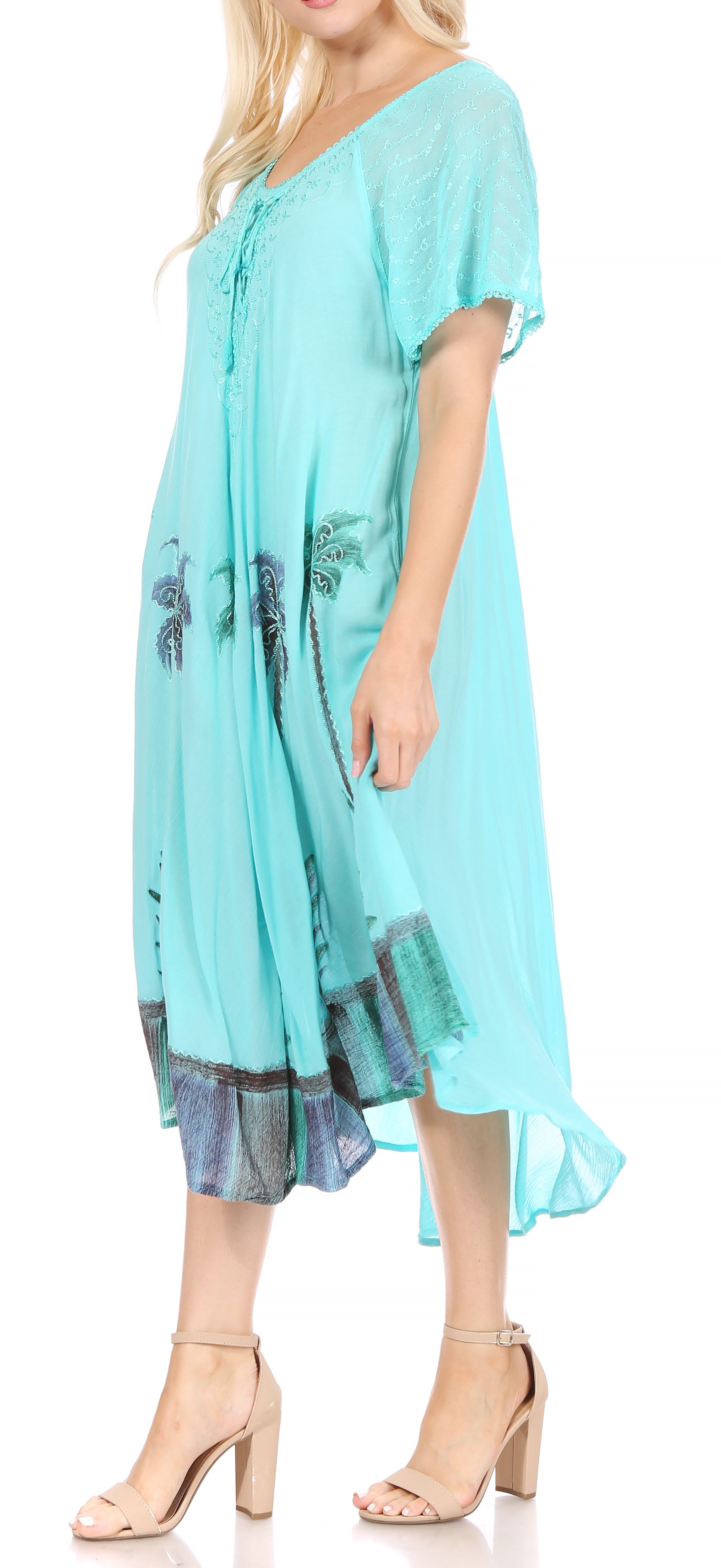 Woman wearing a light blue dress with embroidery, standing against a white background
