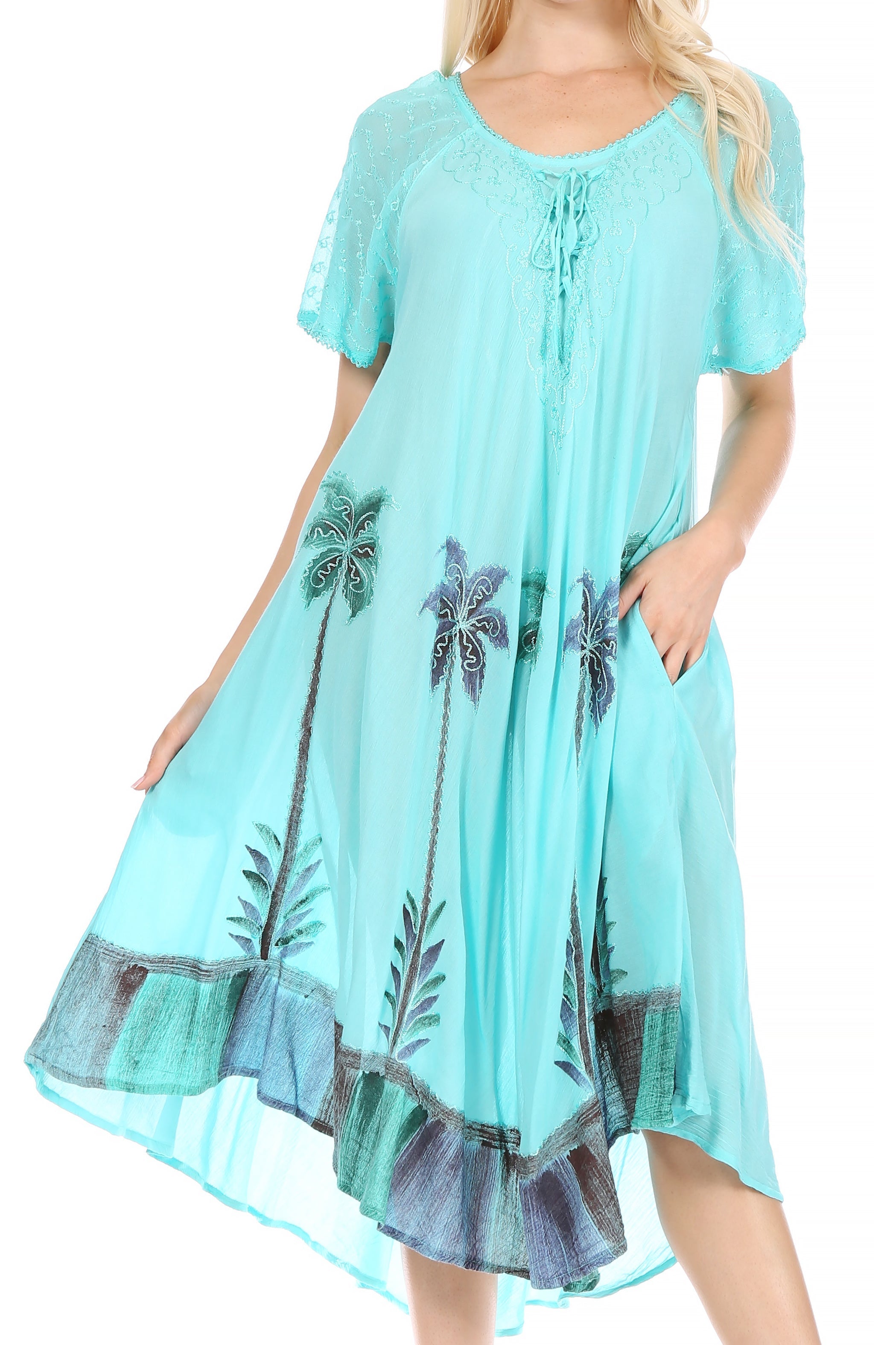 Turquoise dress with palm tree patterns worn by a model on a white background