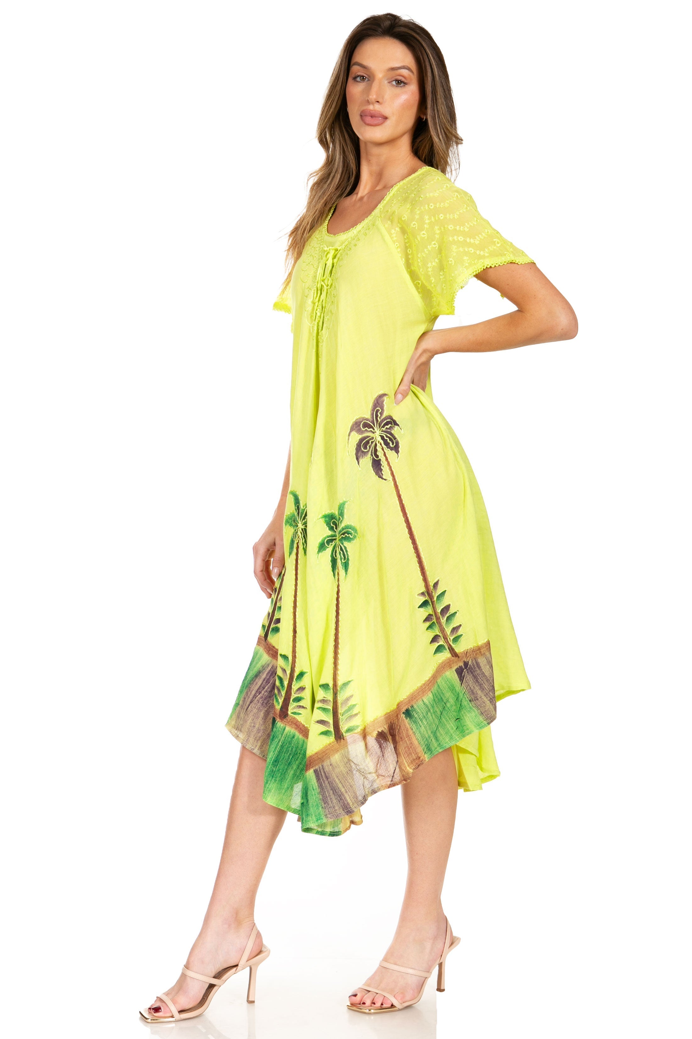 Woman wearing a bright yellow dress with palm tree designs on a white background