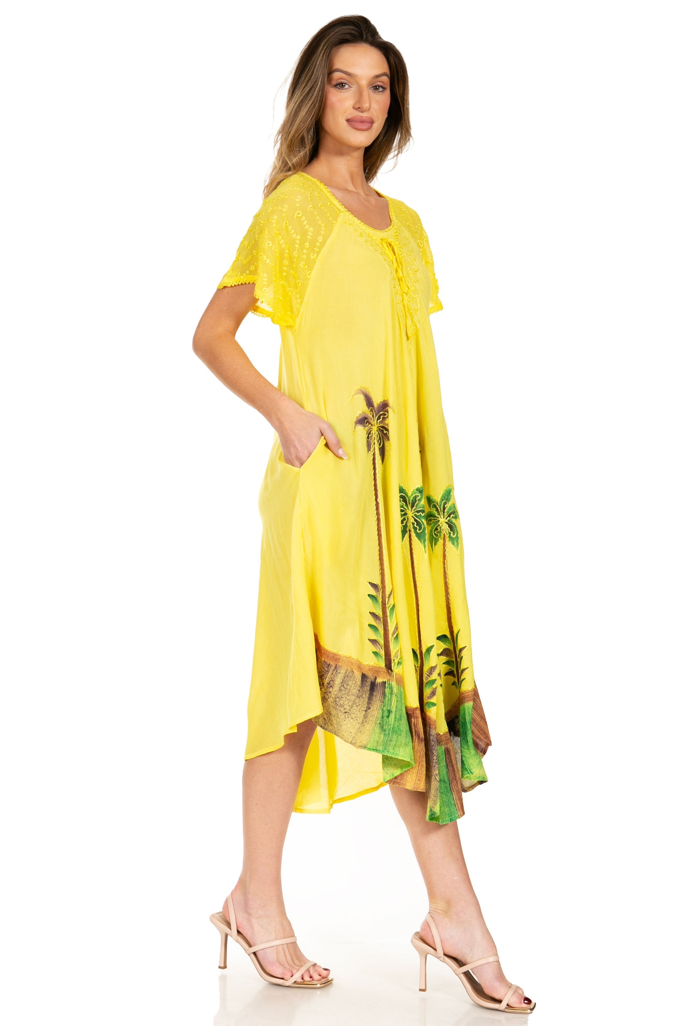 Woman wearing a yellow dress with tropical leaf patterns on a white background