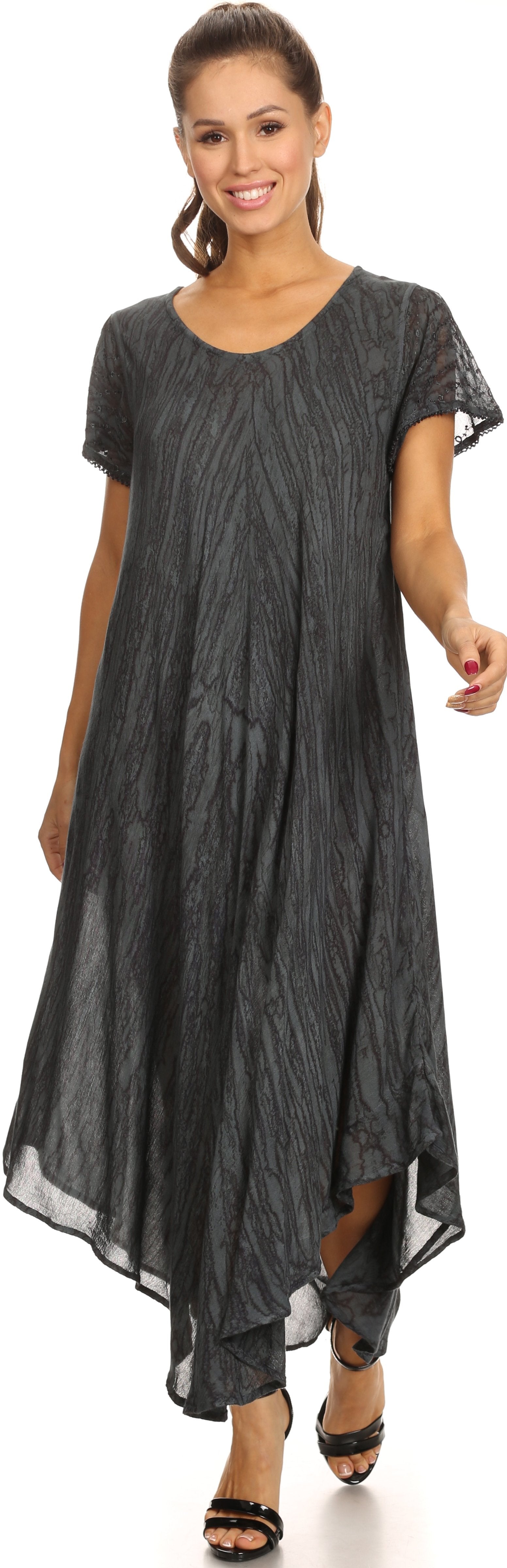 Woman wearing a long, dark gray dress with sheer sleeves on a white background