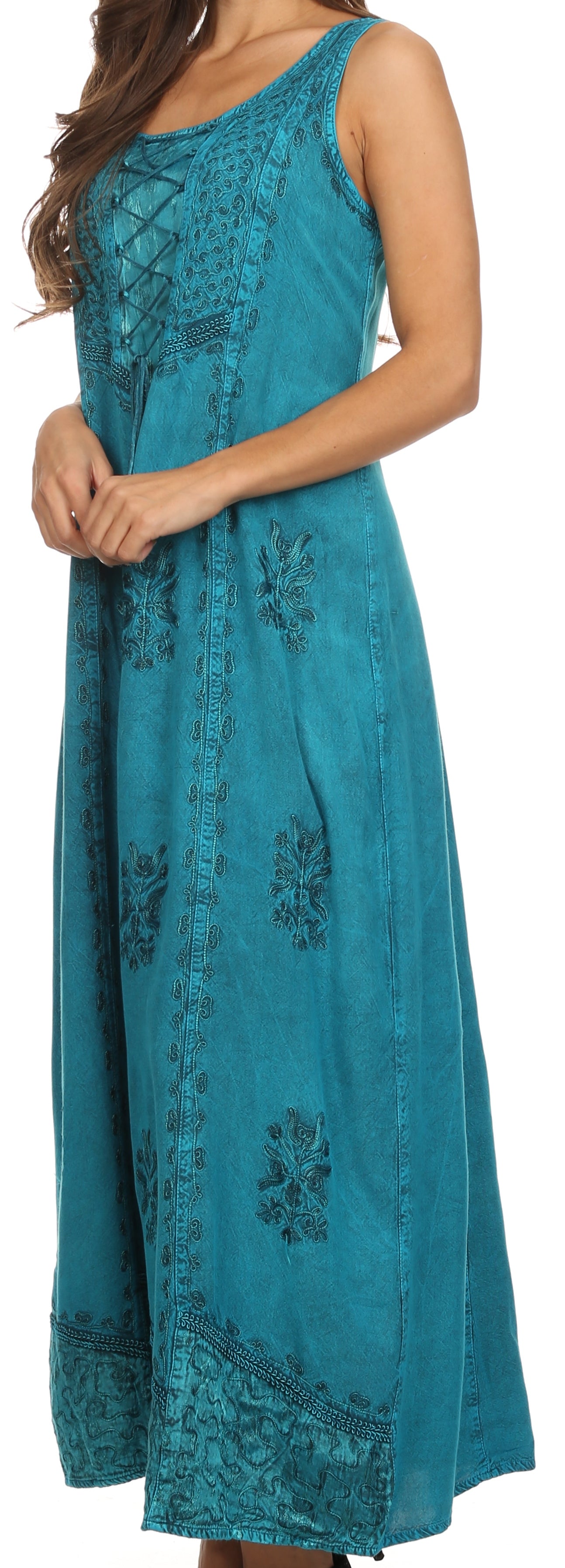 Woman wearing a teal dress with floral embroidery on a plain background
