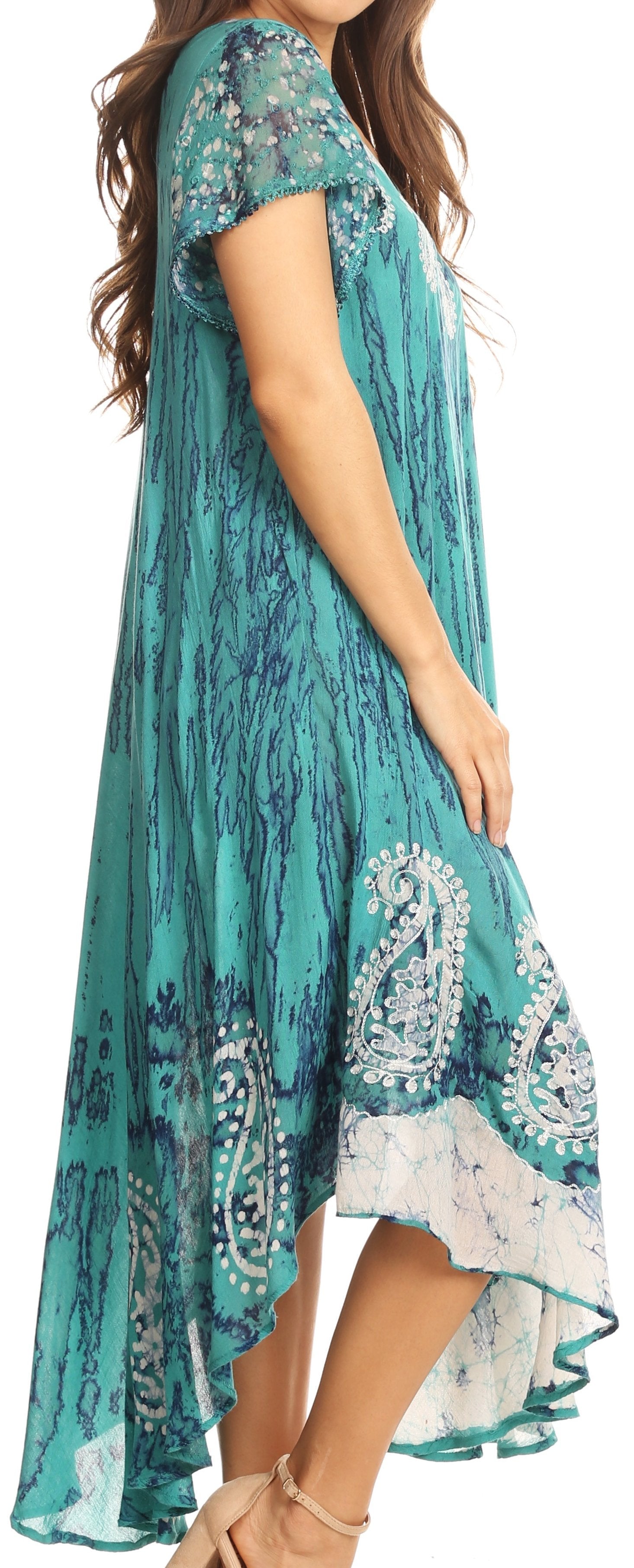 Woman wearing a teal dress with white floral patterns on a plain background