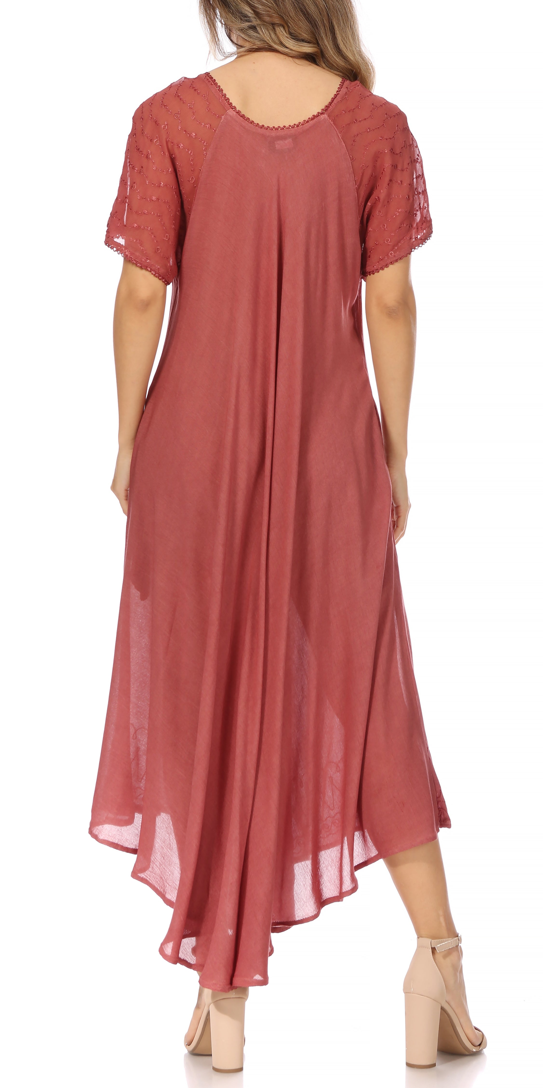 Woman wearing a long, flowing rust-colored dress with lace sleeves on a white background